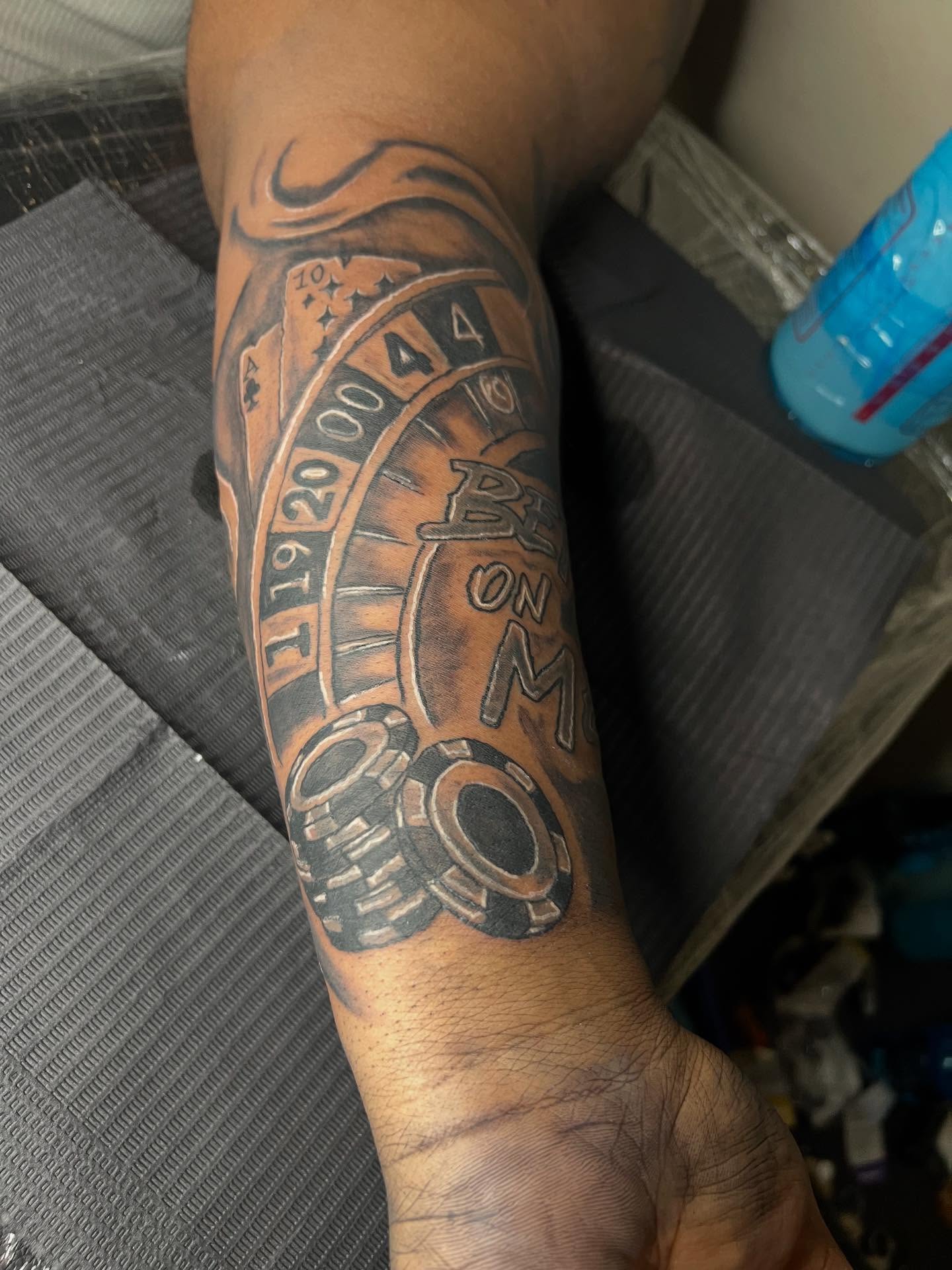 Roulette wheel black and grey tattoo on the forearm by Illuminink.gallery