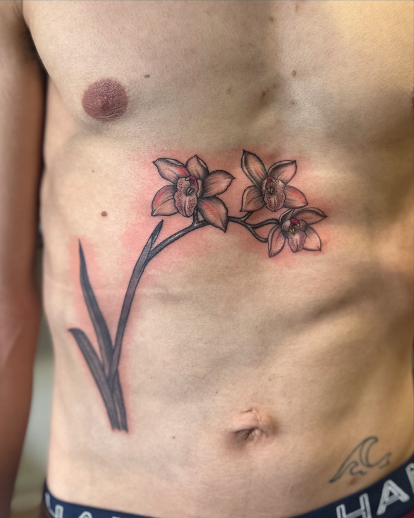 Orchid realism tattoo on the chest by Roxanne Ochoa