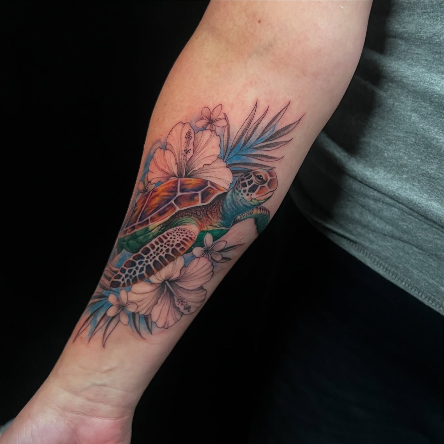 Sea turtle and flowers realism tattoo on the forearm by Chelsea Speirs