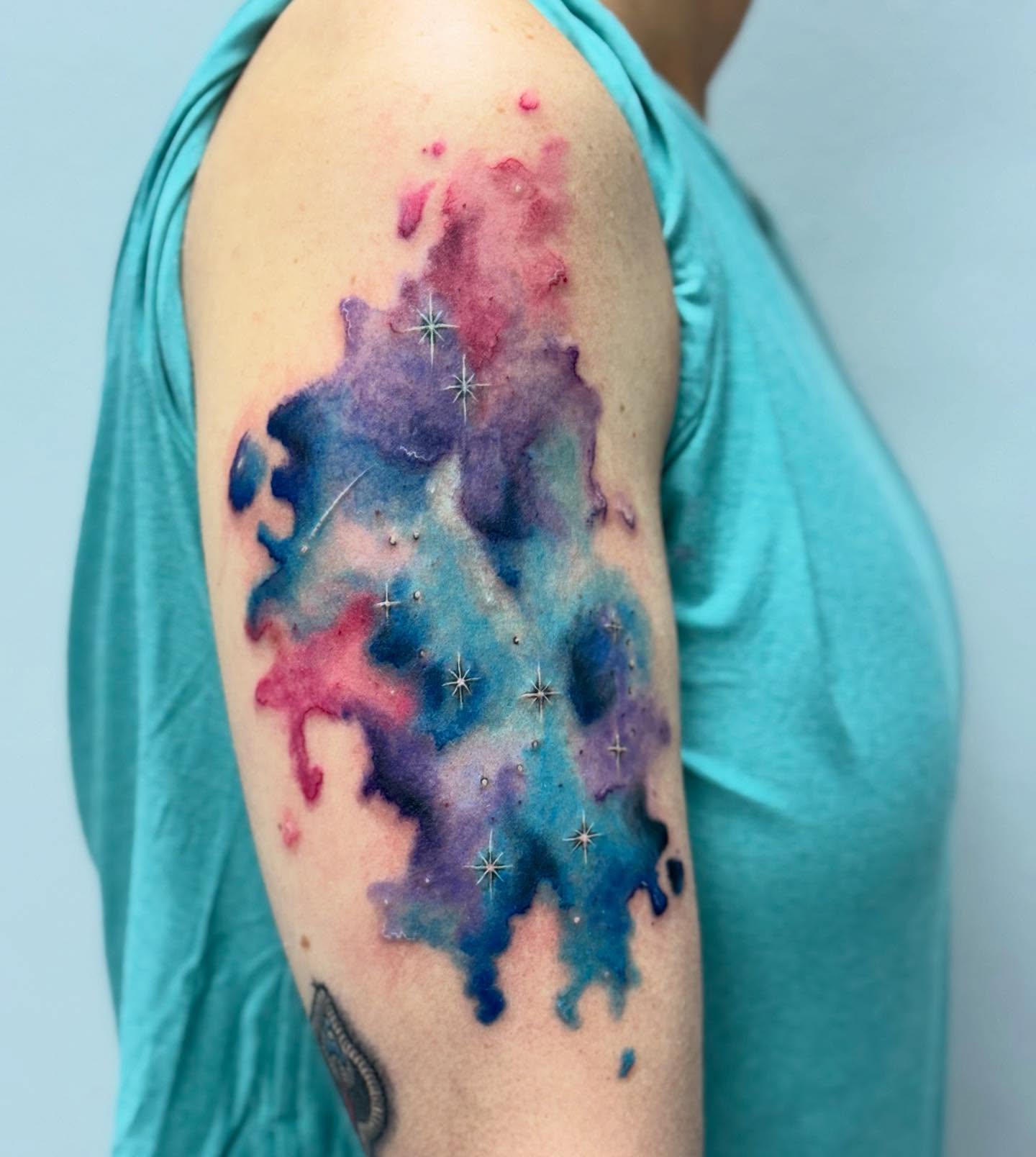 Galaxy watercolor tattoo on the upper arm by Lacee-Beth Finch