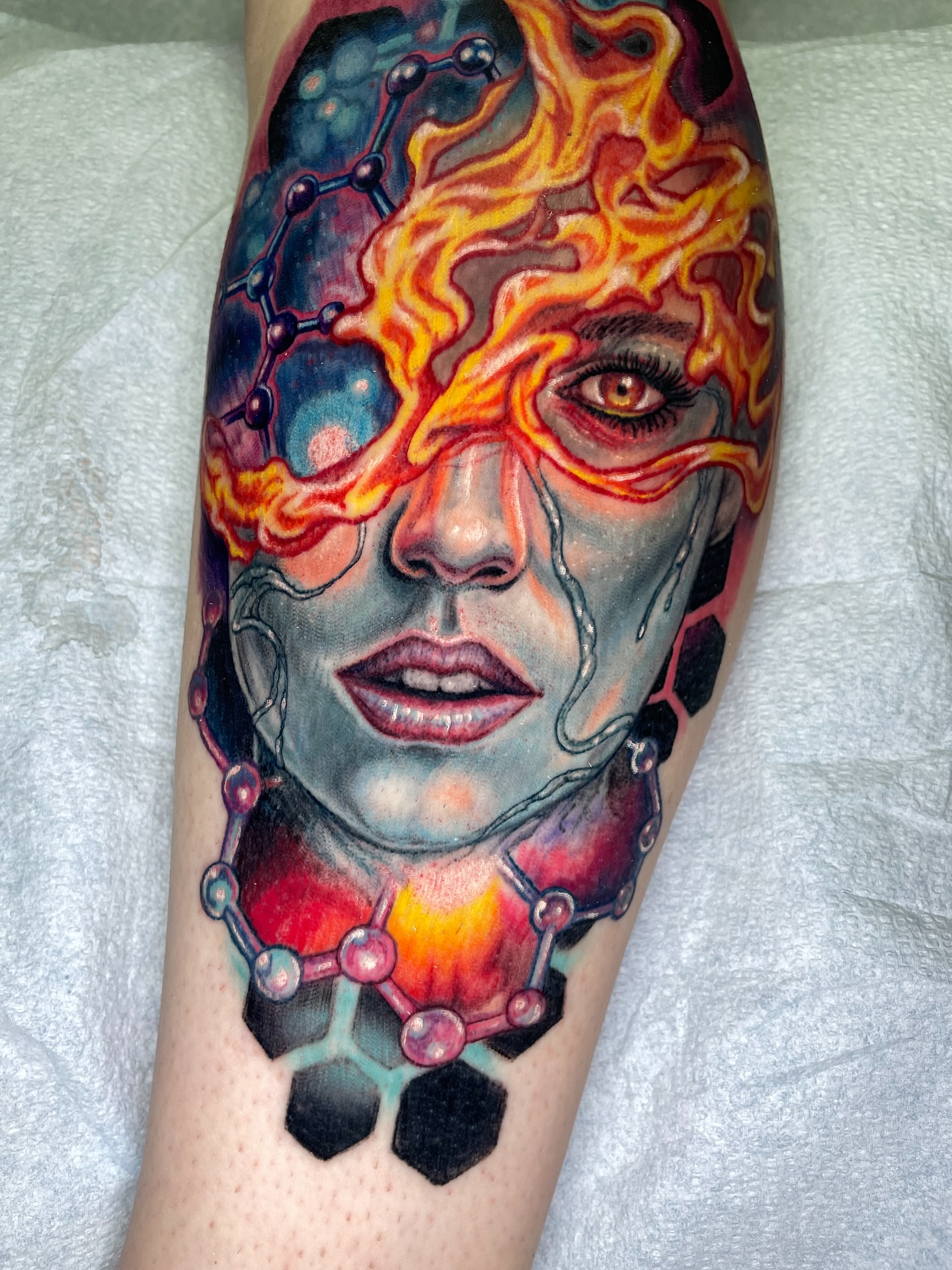 Chemical structure with human face geometric tattoo on the forearm by Rick Elliott