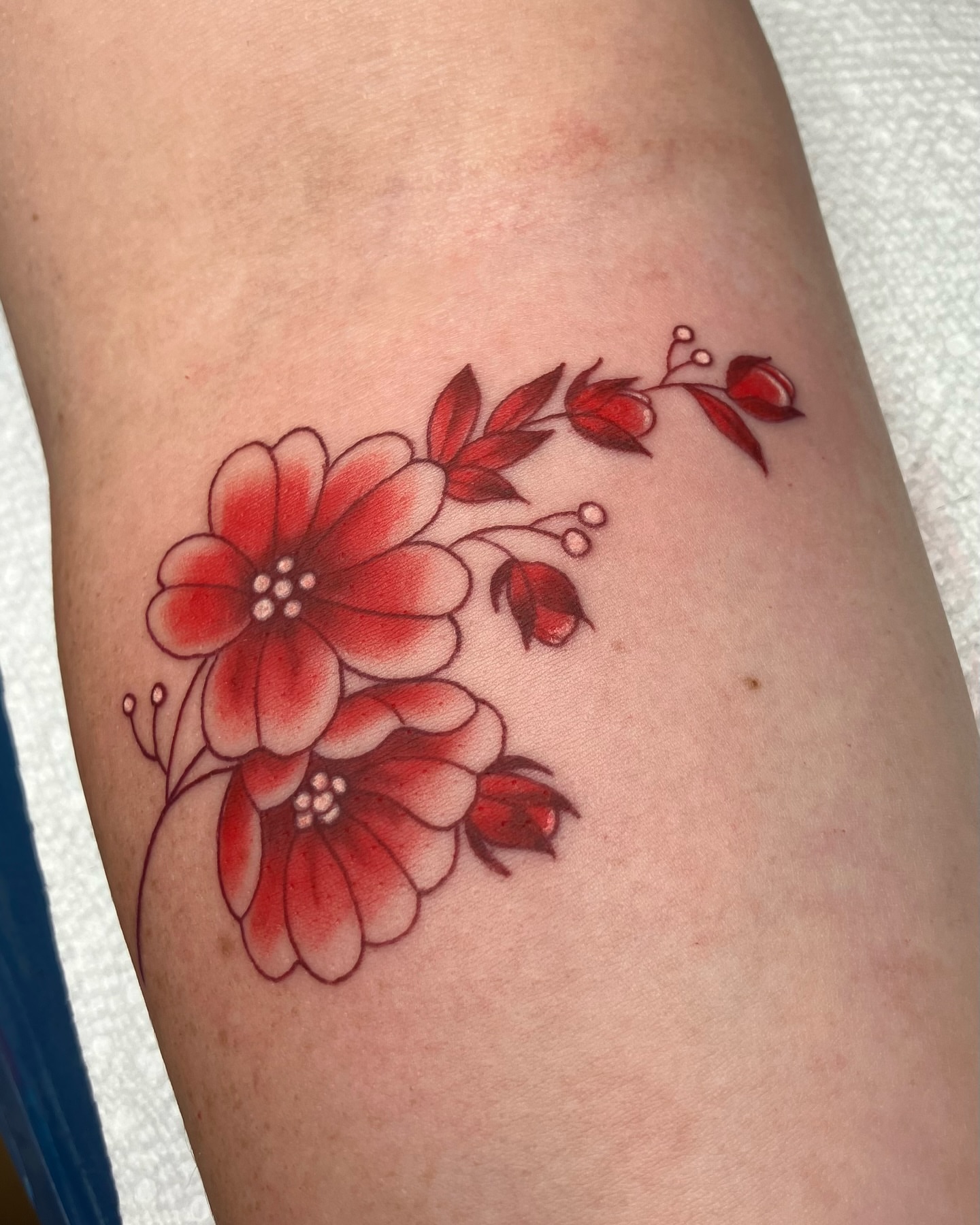 Red floral arrangement dotwork tattoo on the forearm by Hunter McGinnis