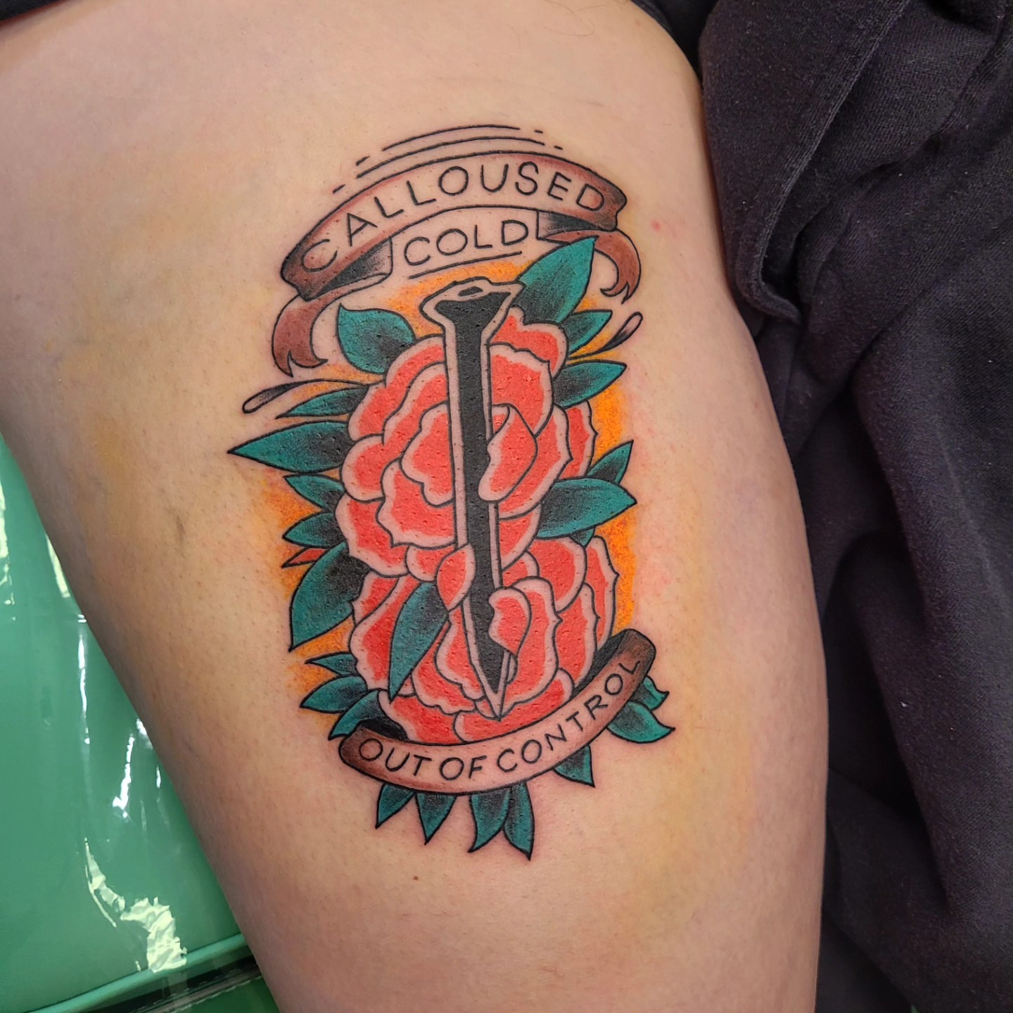 Nail and roses American traditional tattoo on the thigh by Wray Saulsberry