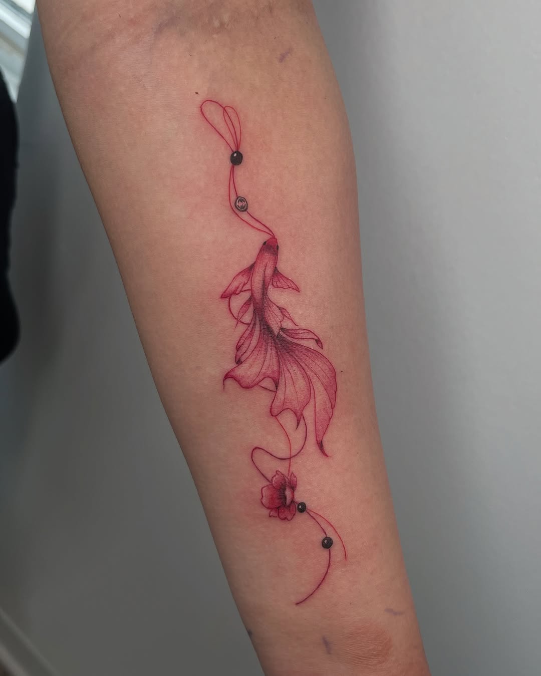 Betta fish with flower and beads fine line tattoo on the forearm by kt
