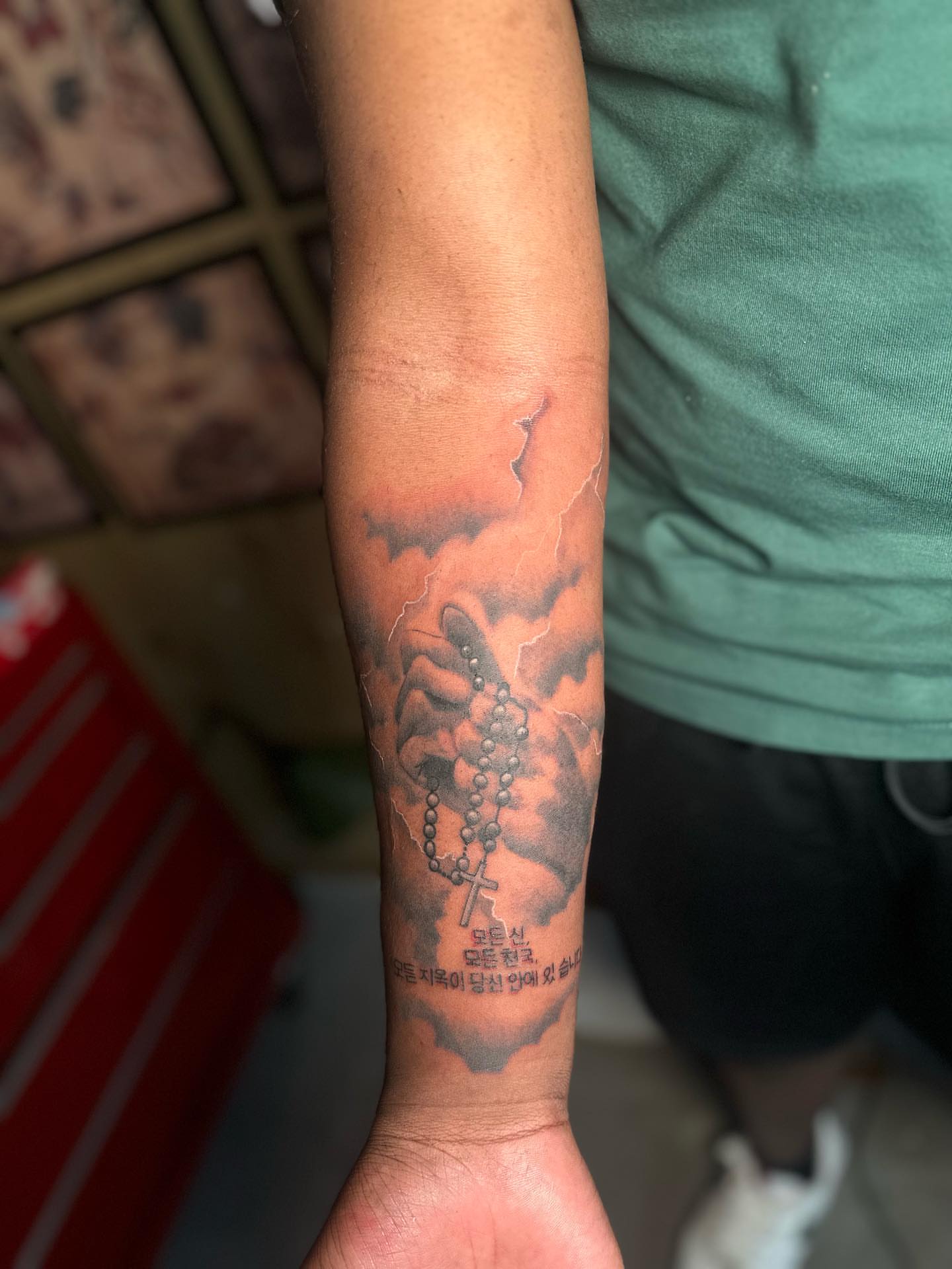 Rosary and cross black and grey tattoo on the forearm by Lee