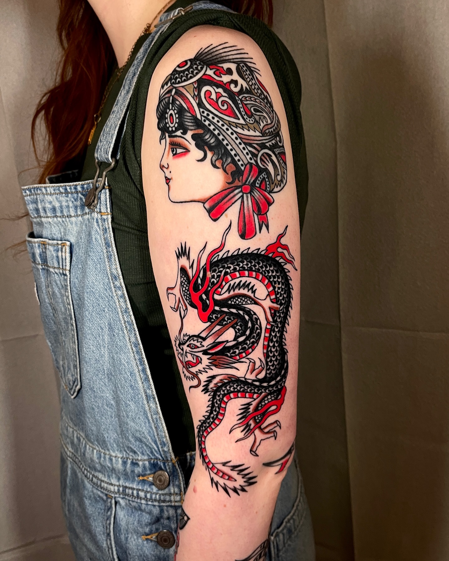 Woman with dragon American traditional tattoo on the upper arm by Chase Tucker