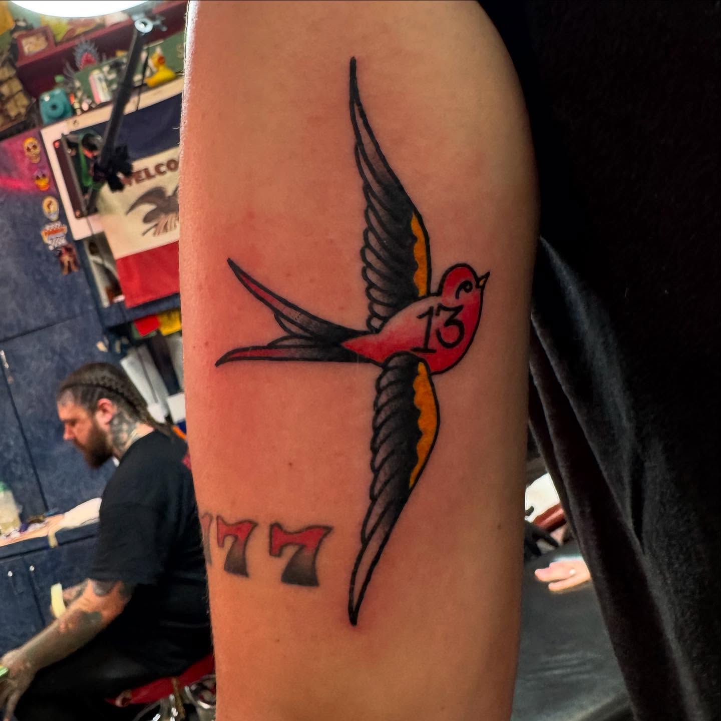 Swallow and number 77 American traditional tattoo on the forearm by Atom Aker