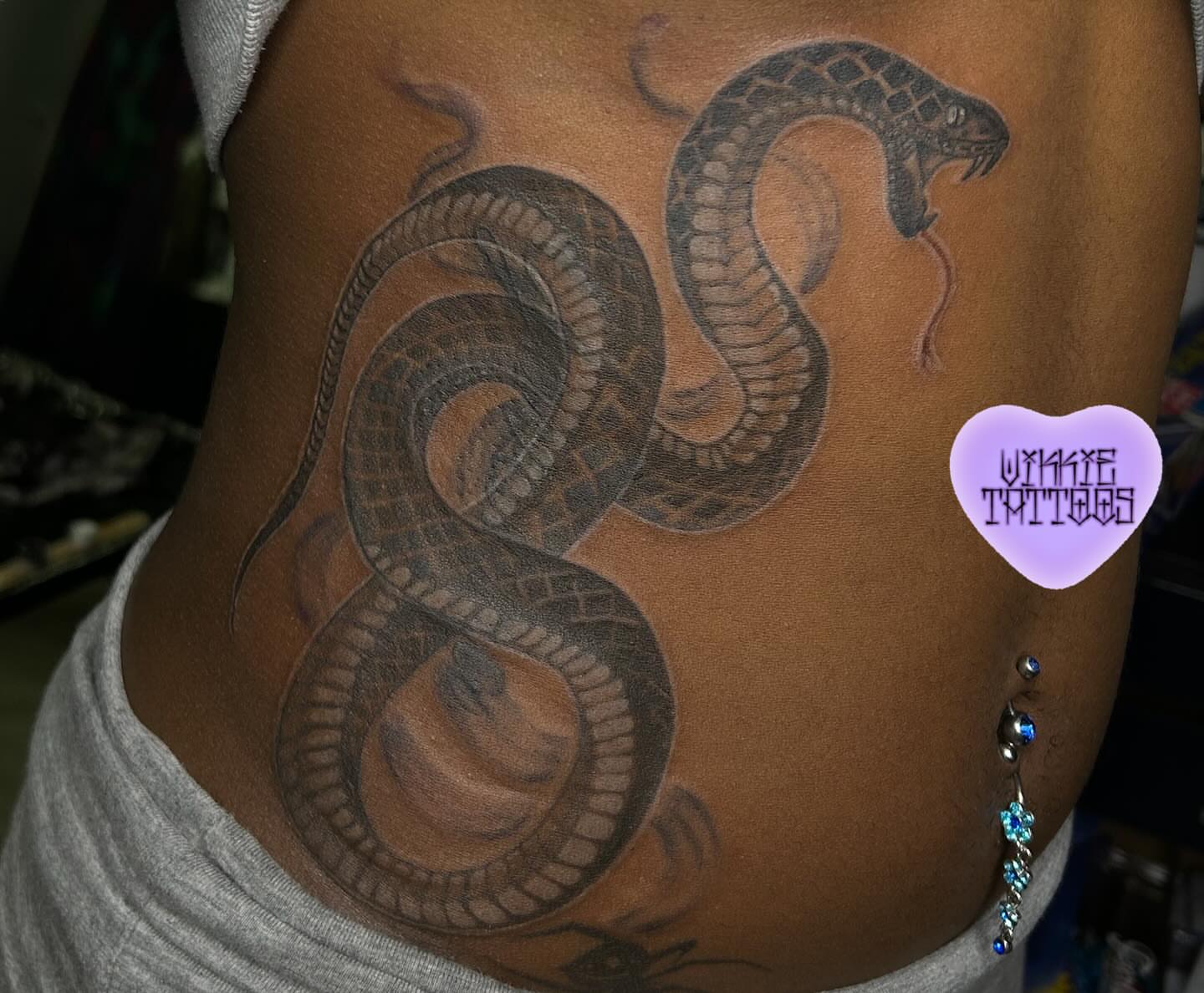 Snake black and grey tattoo on the thigh by Victoria Mendez