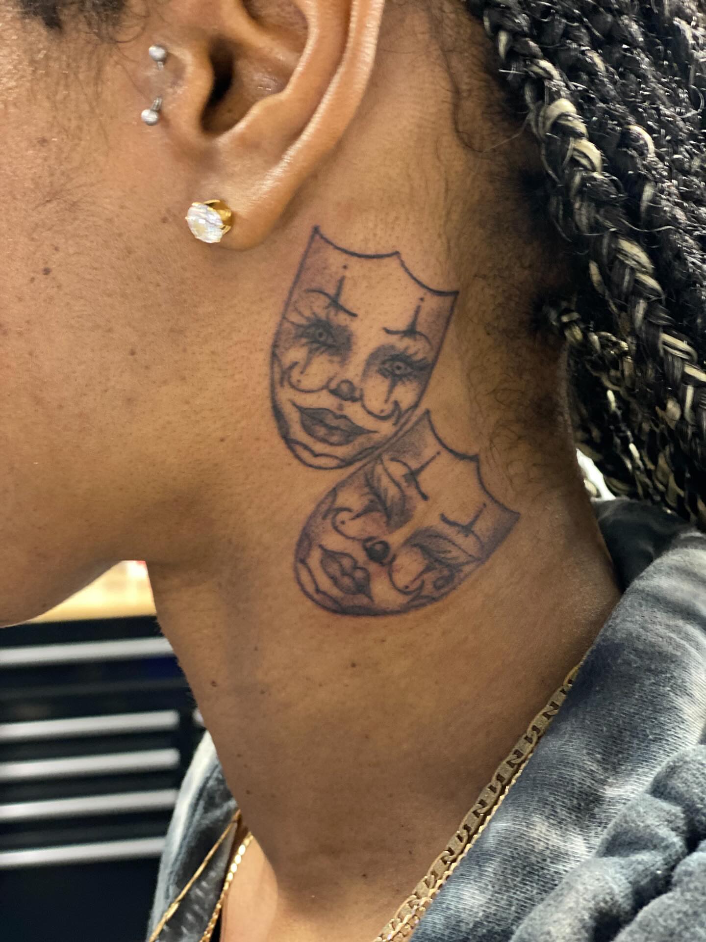 Mask black and grey tattoo on the neck by Chino's Tattoos