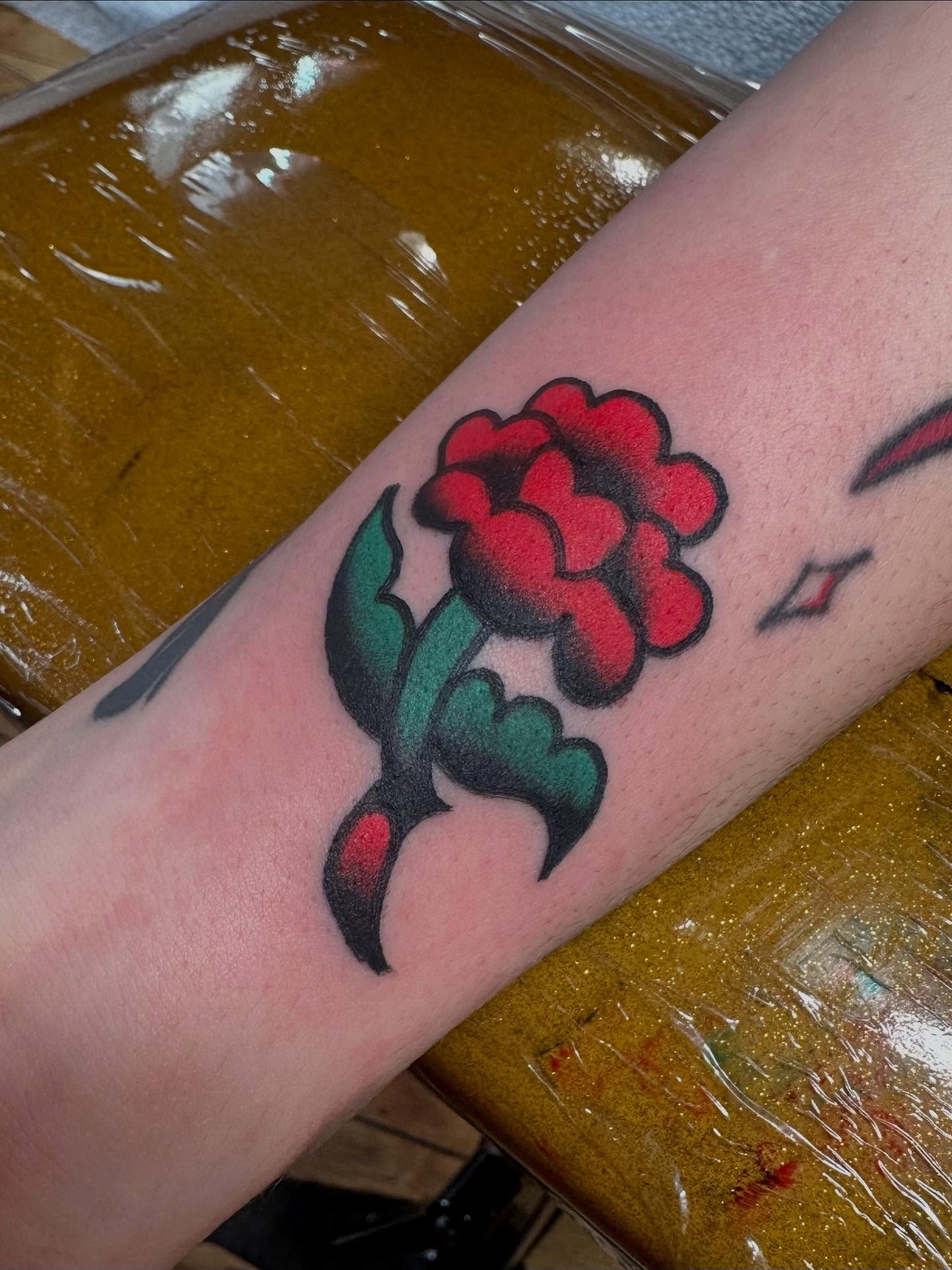 Red flower American traditional tattoo on the forearm by Steven