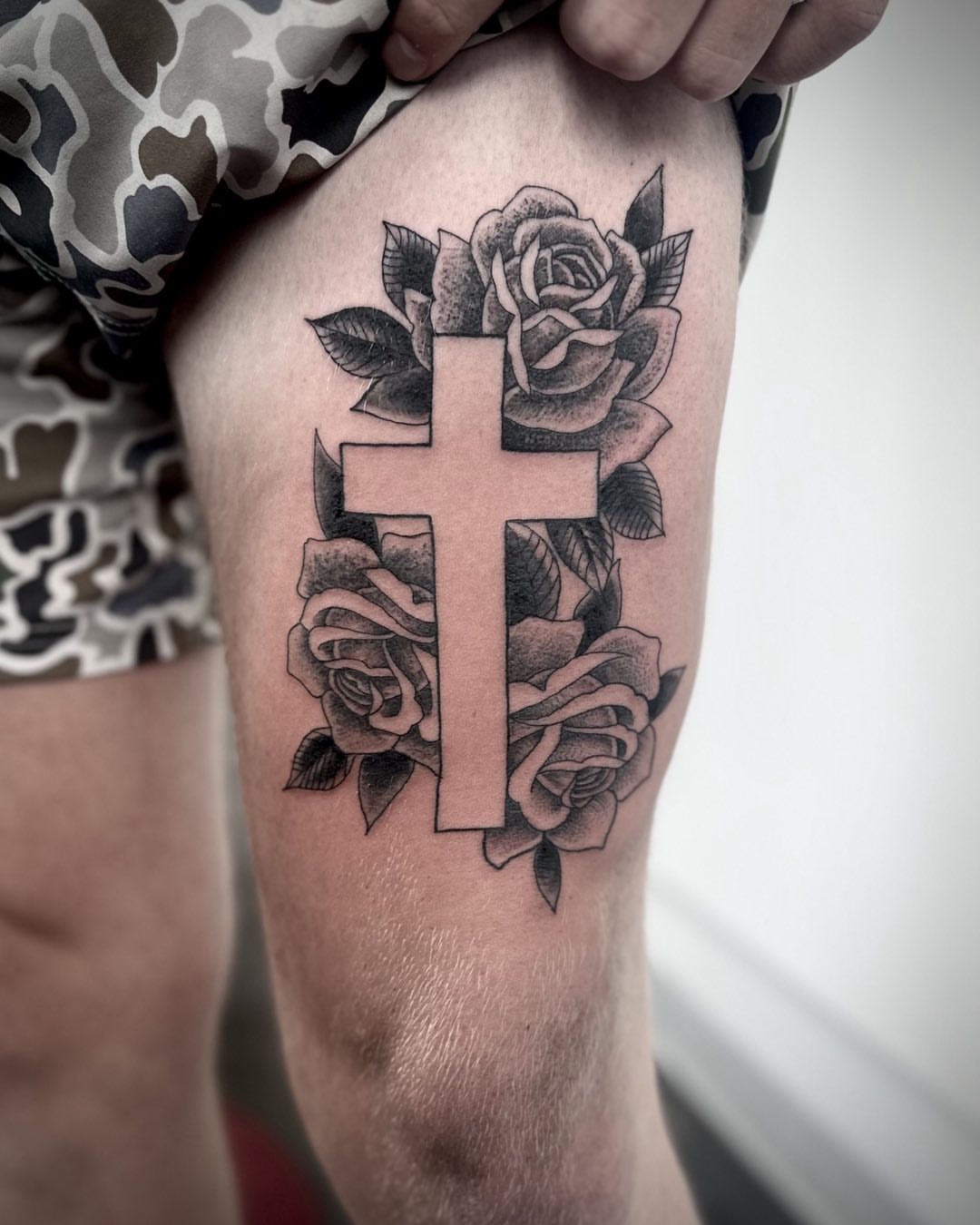Cross with roses realism tattoo on the thigh by Hayden Abernathy