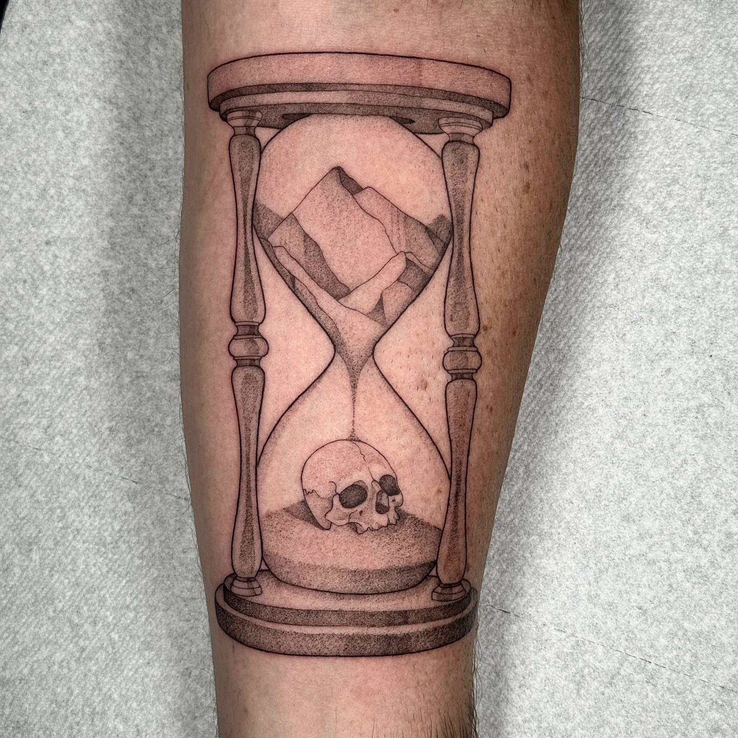 Hourglass with skull black and grey tattoo on the forearm by Molly Murray