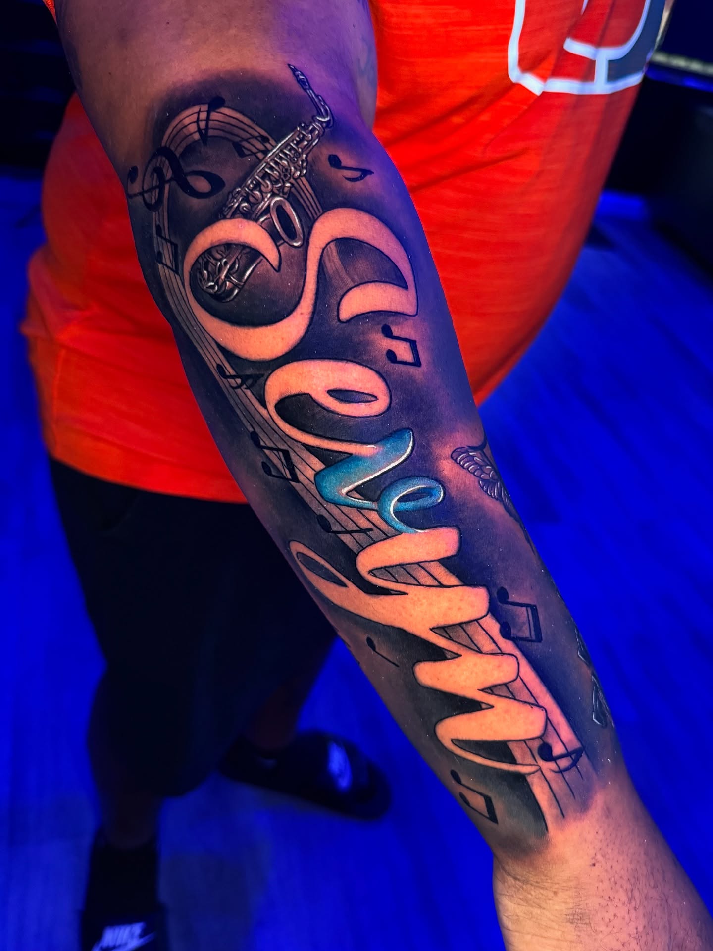Music notes and cursive text lettering script tattoo on the forearm by Raw Hound, Hialeah, Florida