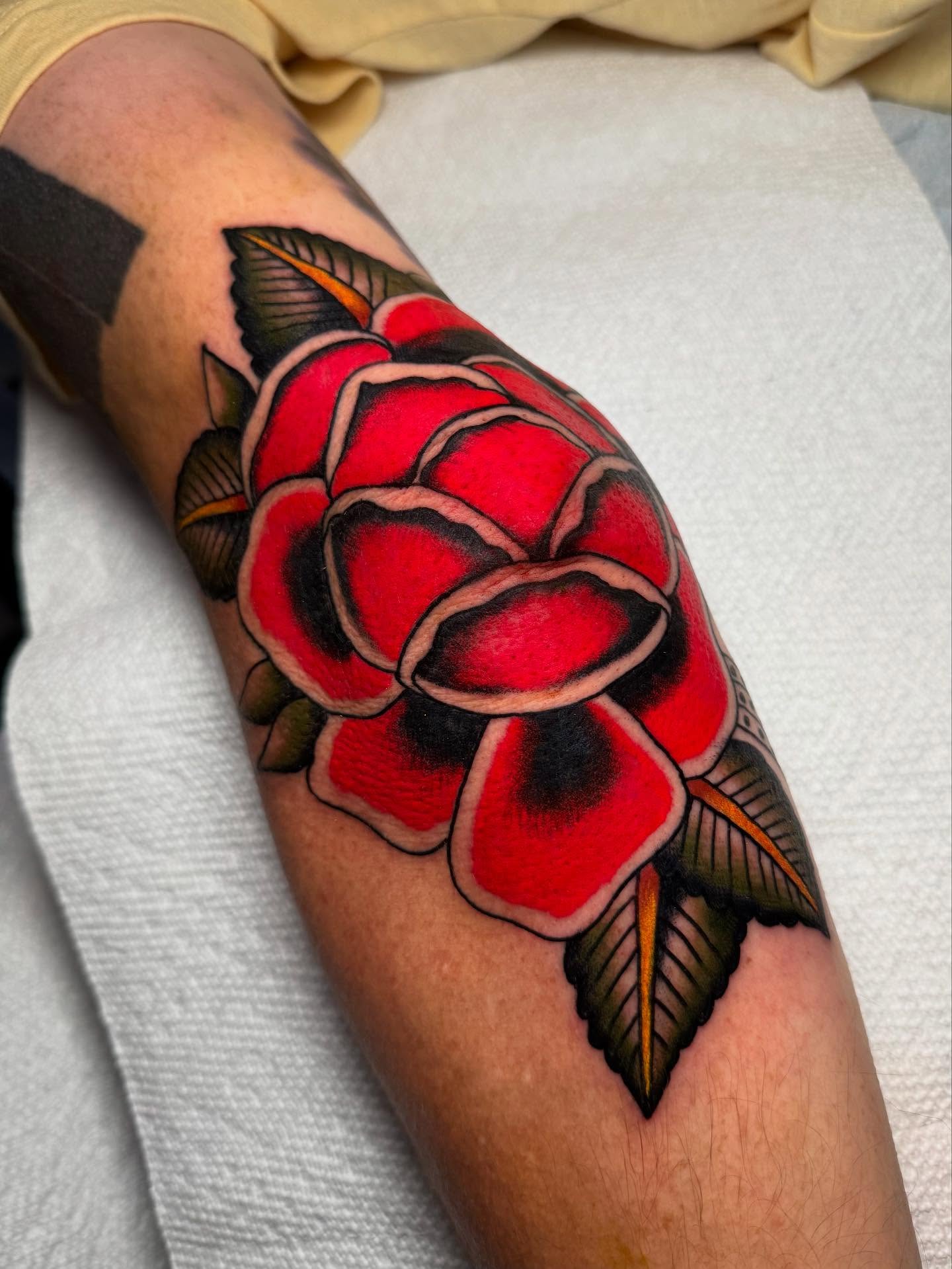 Red rose American traditional tattoo on the forearm by Cody Petkus