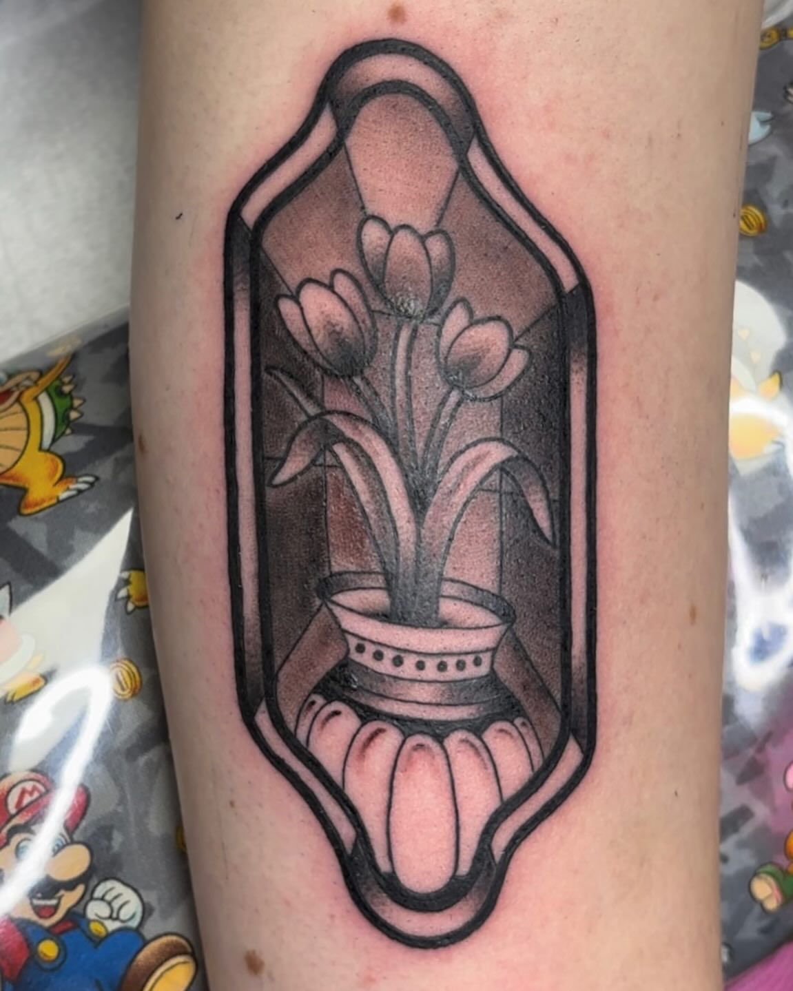 Flowers in a glass vase black and grey tattoo on the forearm by Molly Dixon