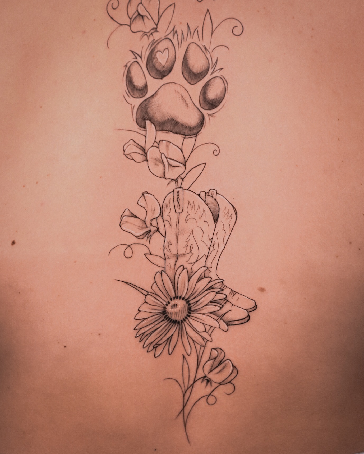 Paw print and flowers black and grey tattoo on the back by Stephanie Shortsleeve