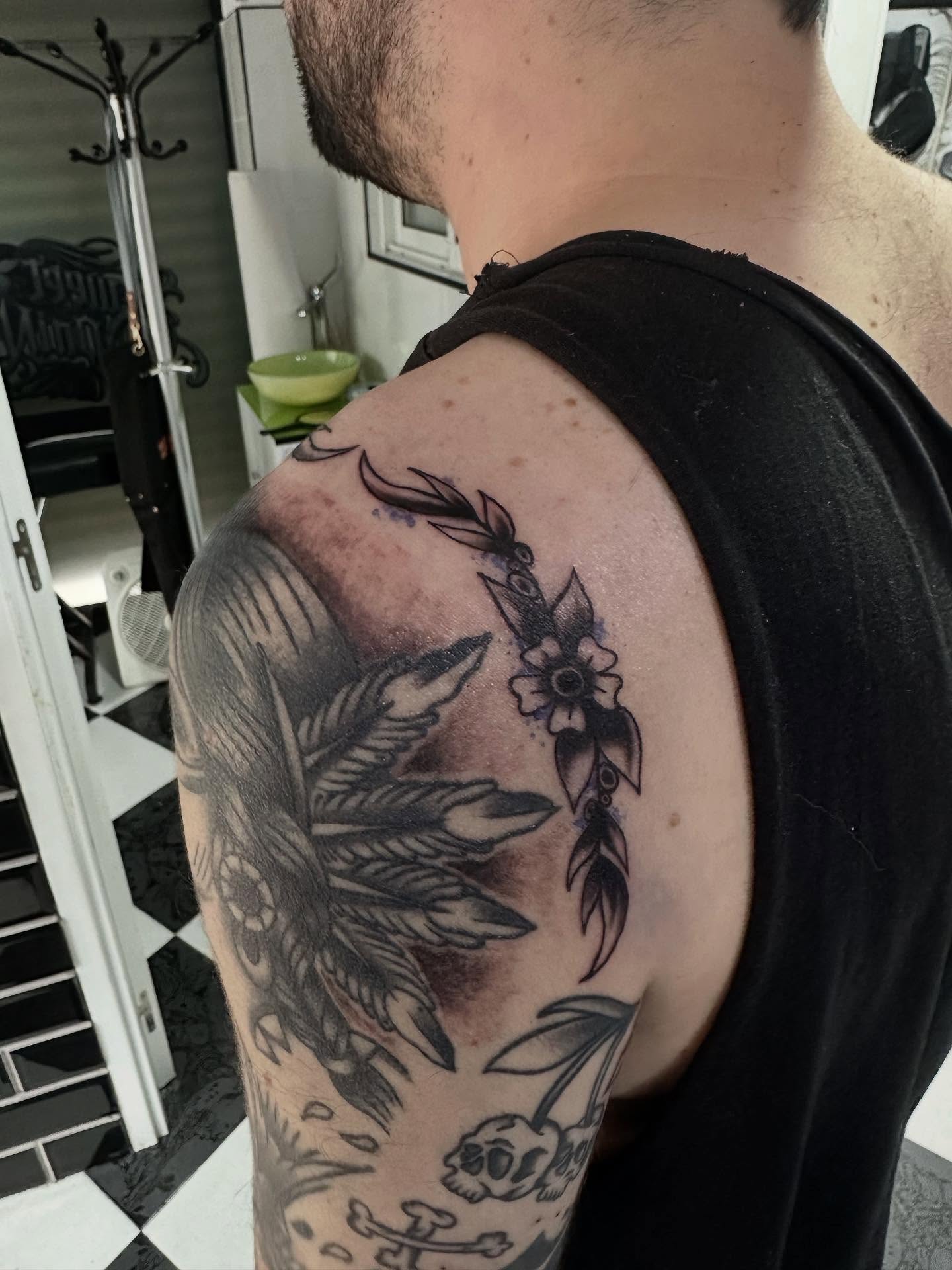 Feather and flower black and grey tattoo on the shoulder by Kunaytattoo