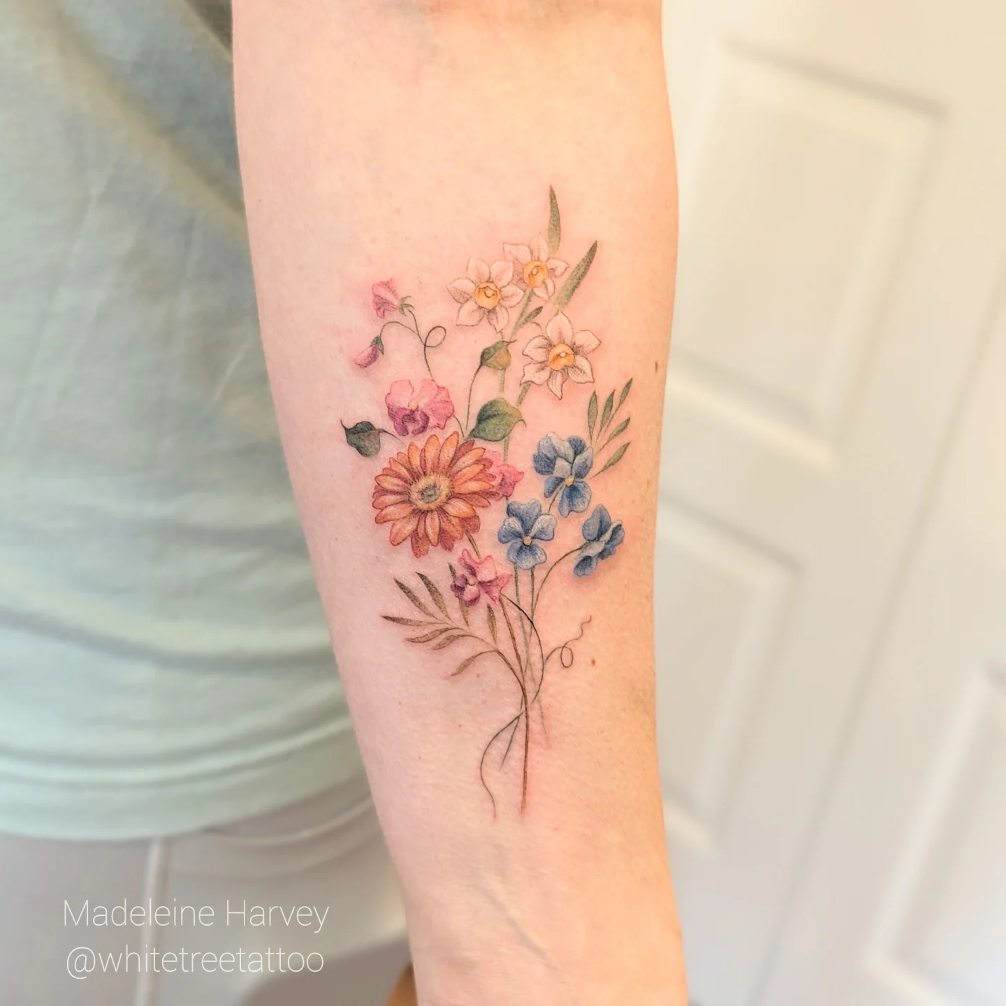 Floral bouquet watercolor tattoo on the forearm by Maddie