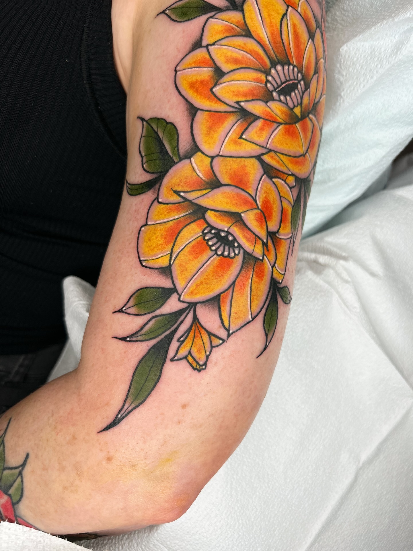 Orange flowers American traditional tattoo on the forearm by Noah Crow