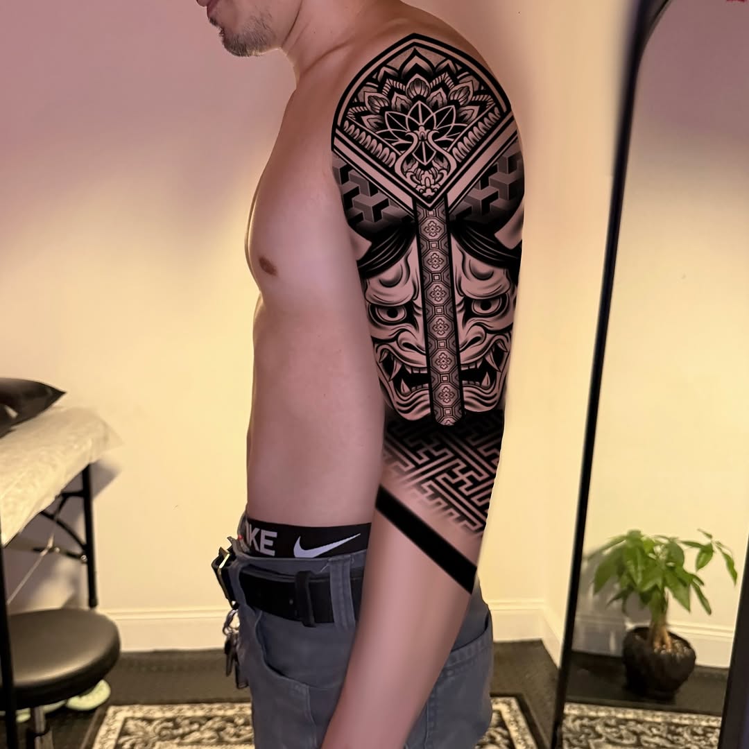 Oni mask and geometric patterns tribal tattoo on the upper arm by Ivy lee