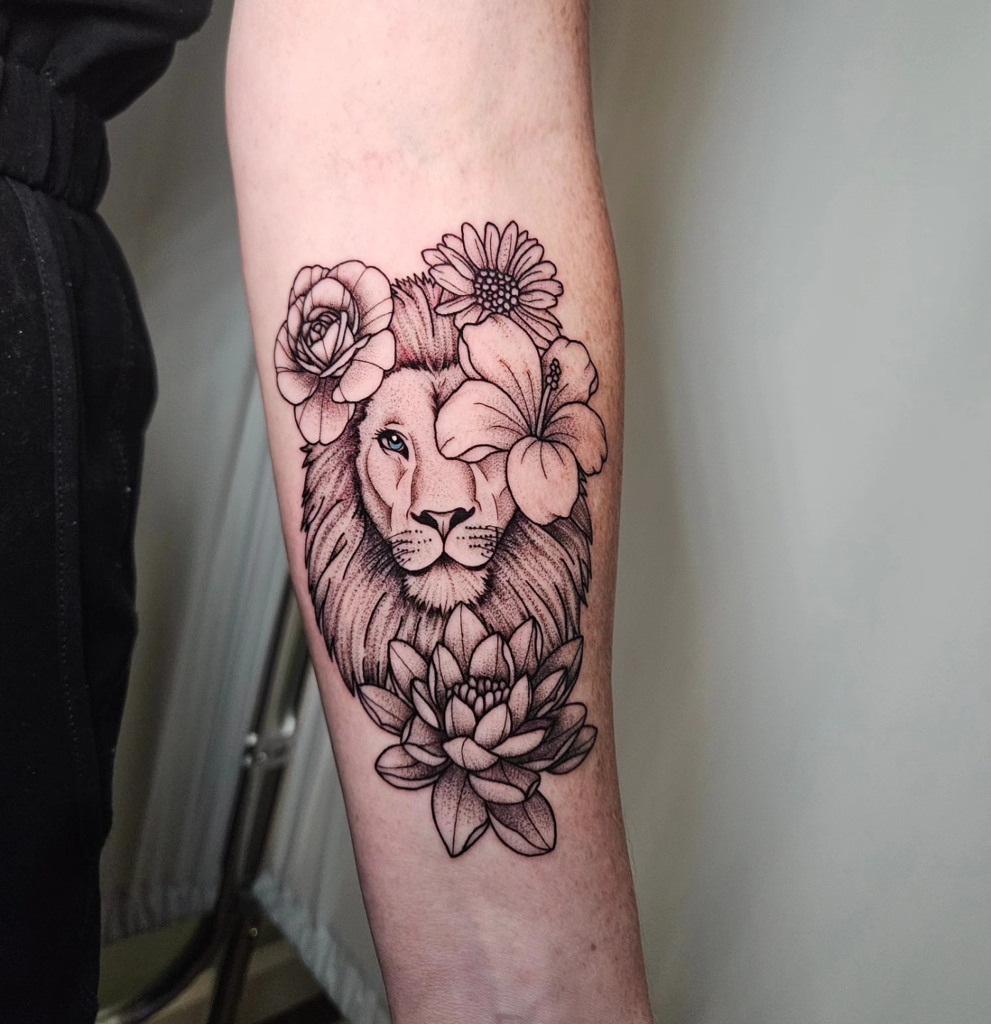 Lion with flowers dotwork tattoo on the forearm by Nicole Bett