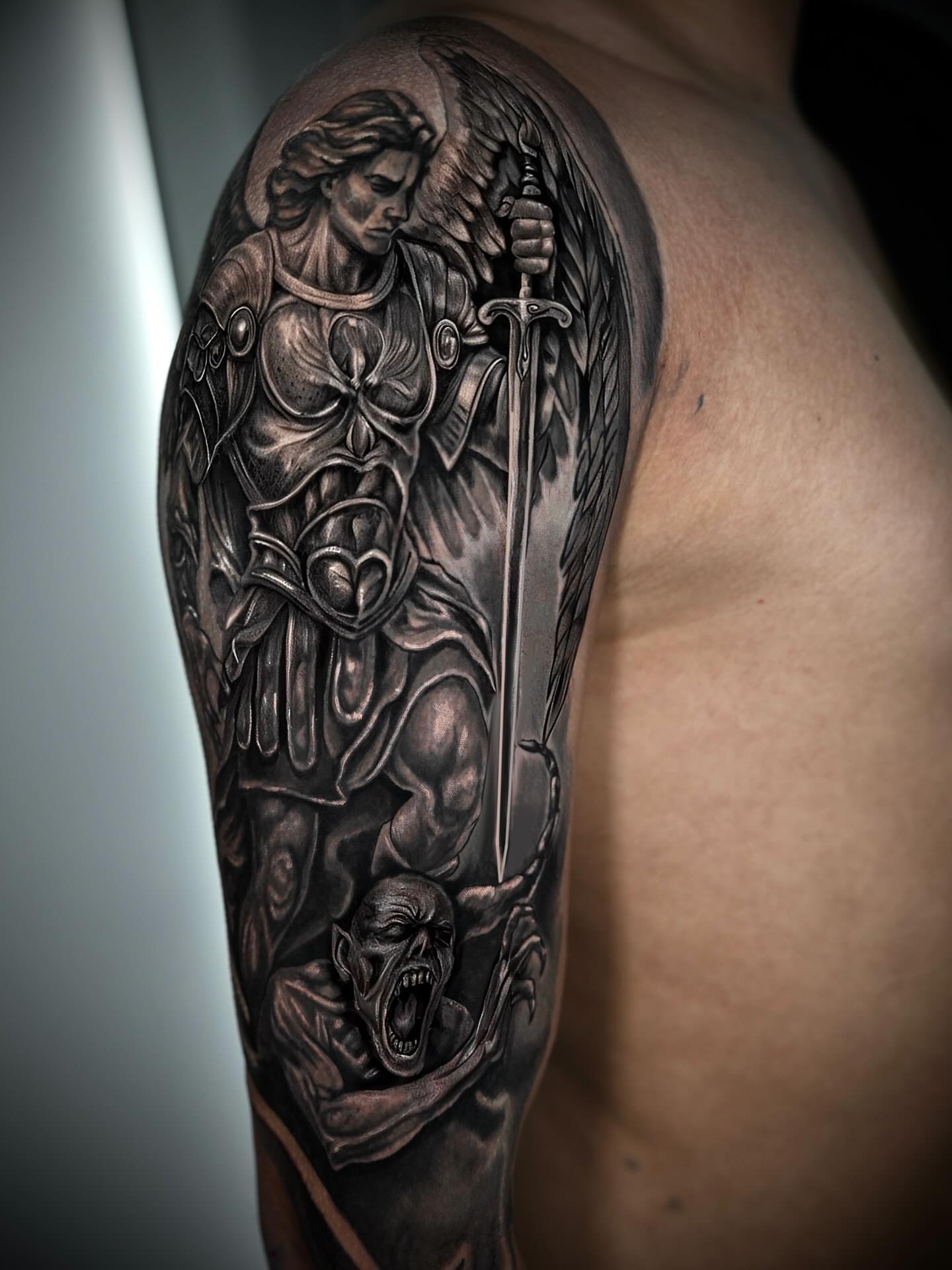 Angel slaying demon realism tattoo on the upper arm by Gabriel Garcia