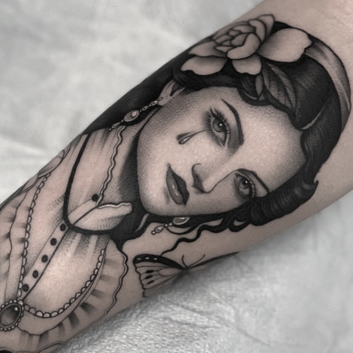 Woman with floral crown realism tattoo on the forearm by Luna Lucero