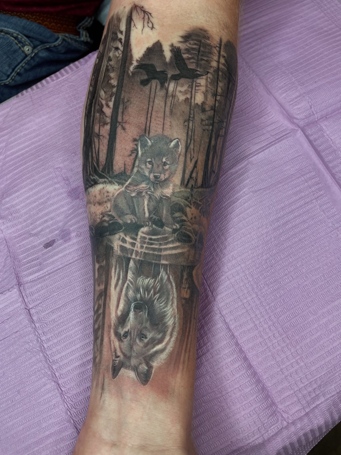 Forest scene with wolf realism tattoo on the forearm by Melissa Rose Moya