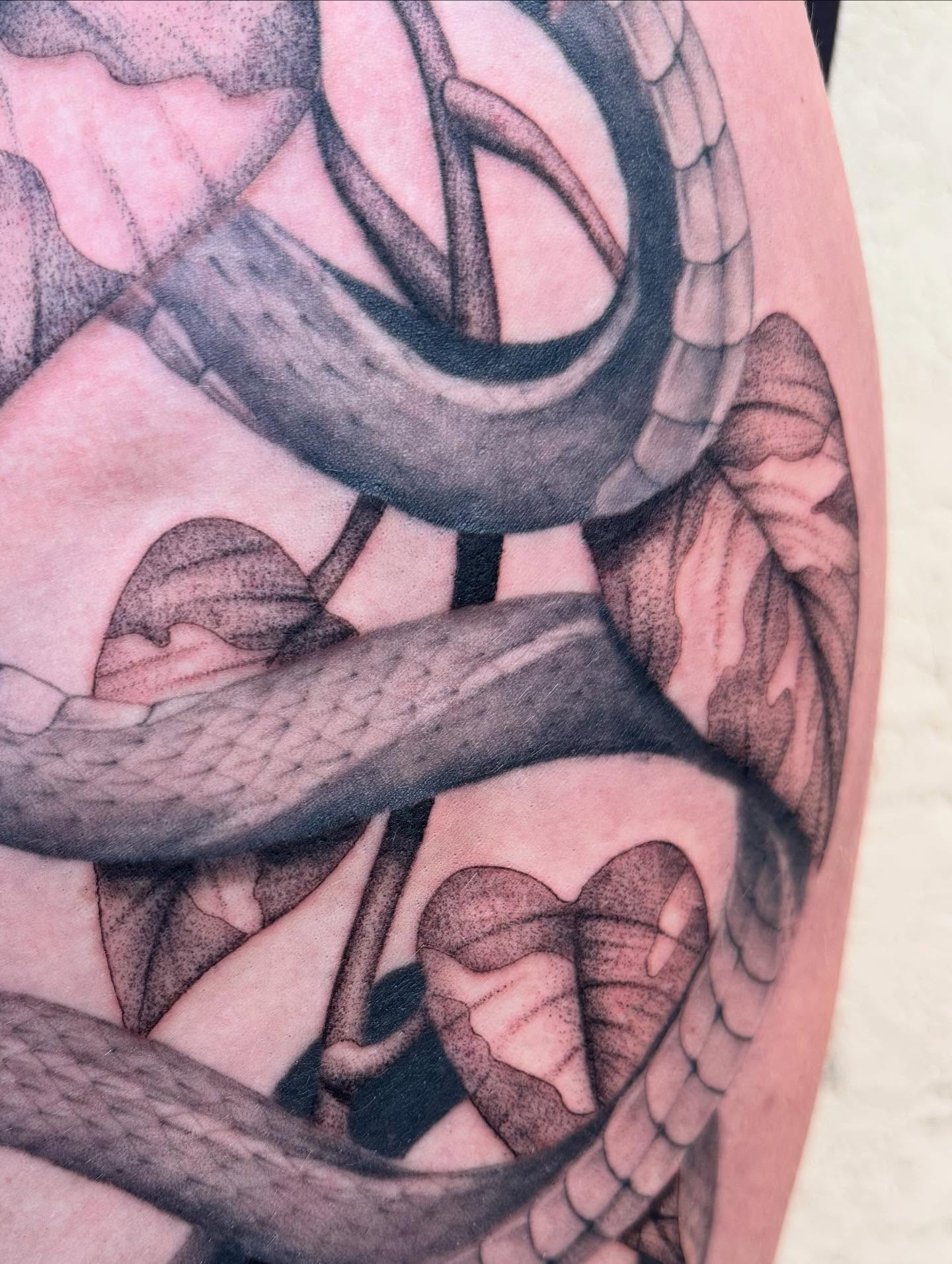 Snake and heart black and grey tattoo on the upper arm by Truett Payton