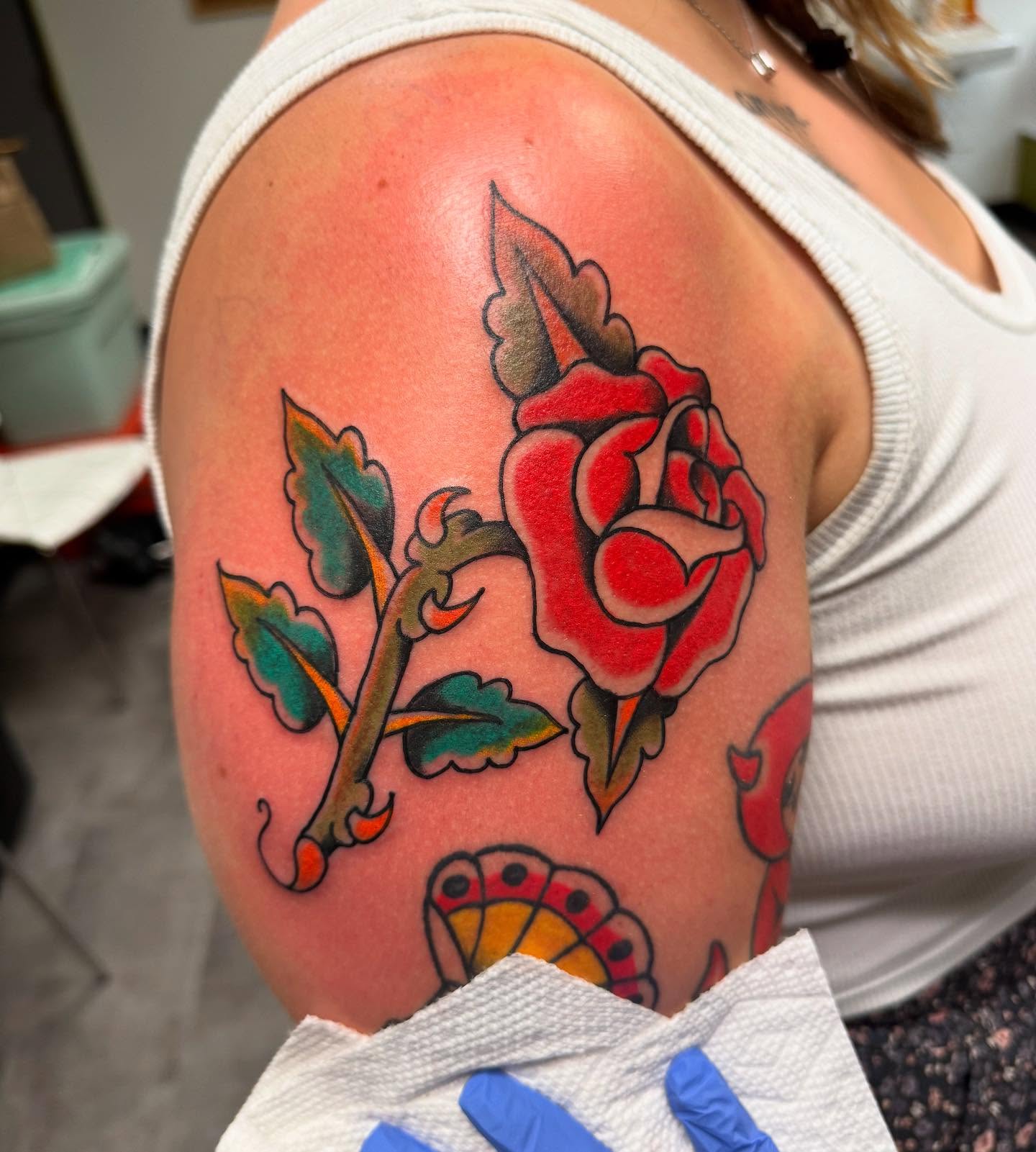 Red rose American traditional tattoo on the shoulder by 𝗞𝗮𝘁 𝗕𝗹𝗮𝗻𝗸𝗲𝗻𝘀𝗵𝗶𝗽