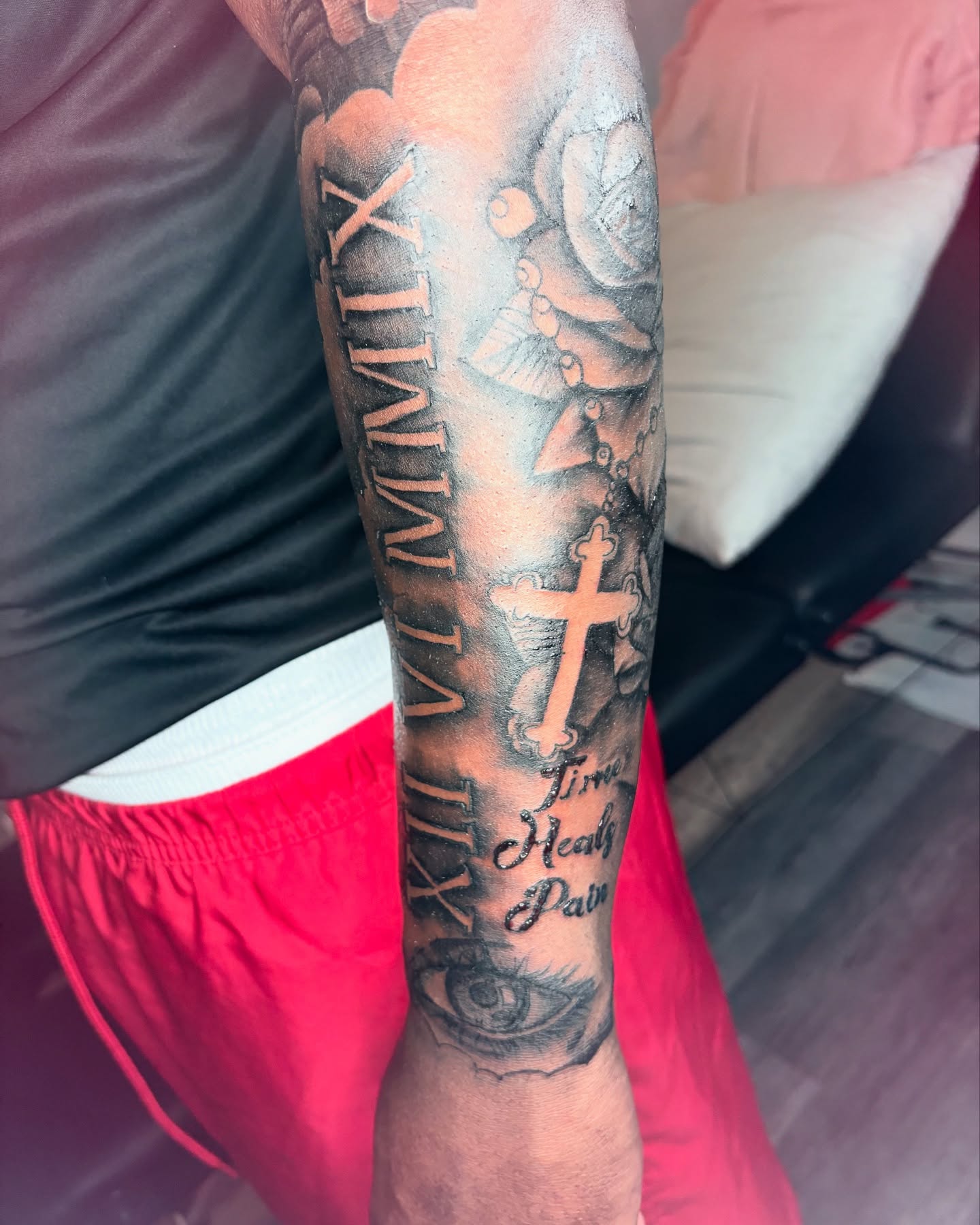 Cross and script black and grey tattoo on the forearm by Maleek Inkz