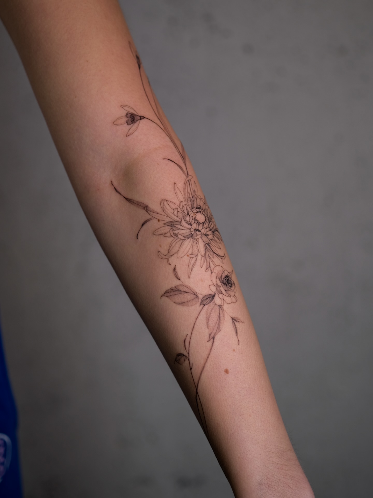 Floral arrangement fine line tattoo on the forearm by Nadia Andriu