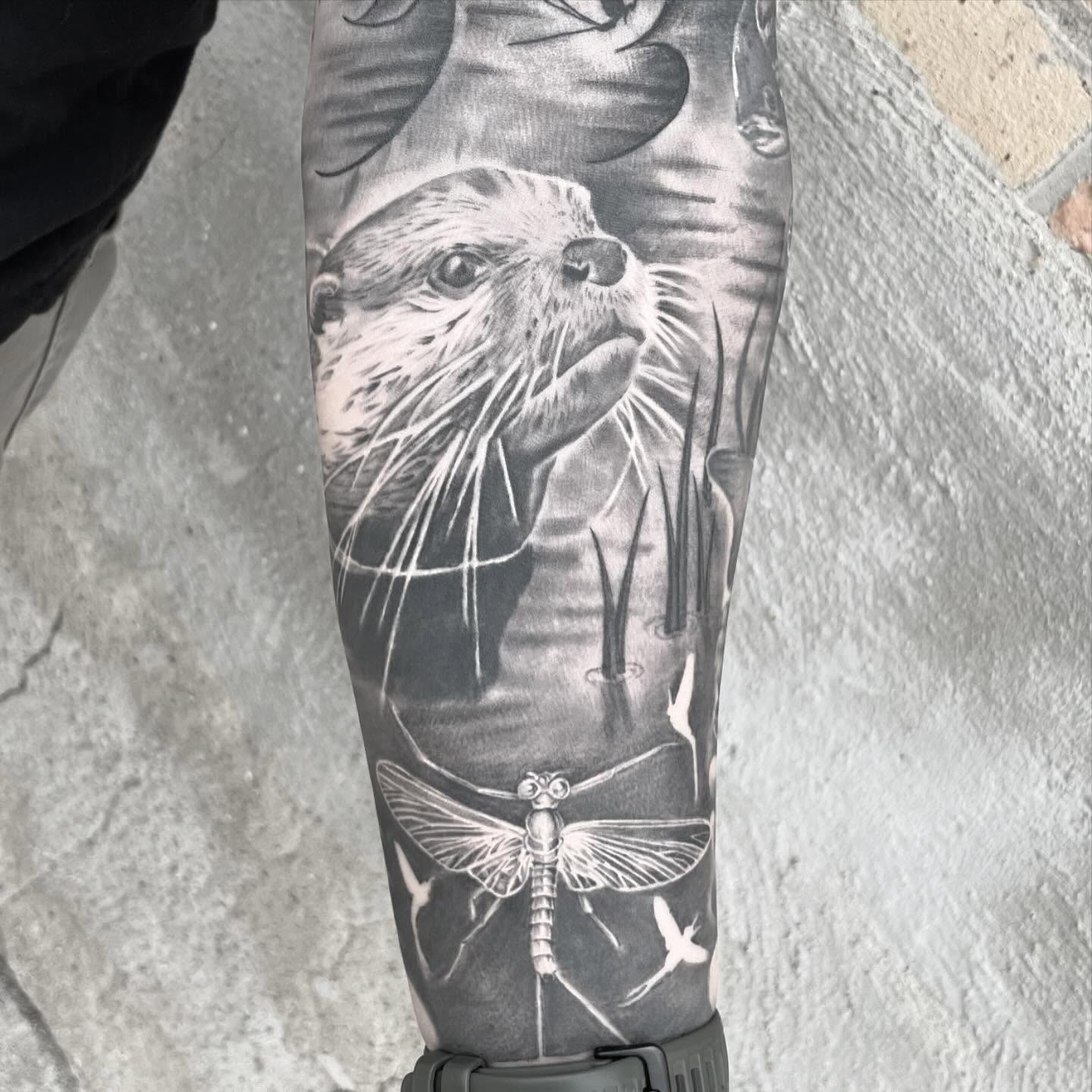 Otter and dragonfly realism tattoo on the forearm by mike hudson
