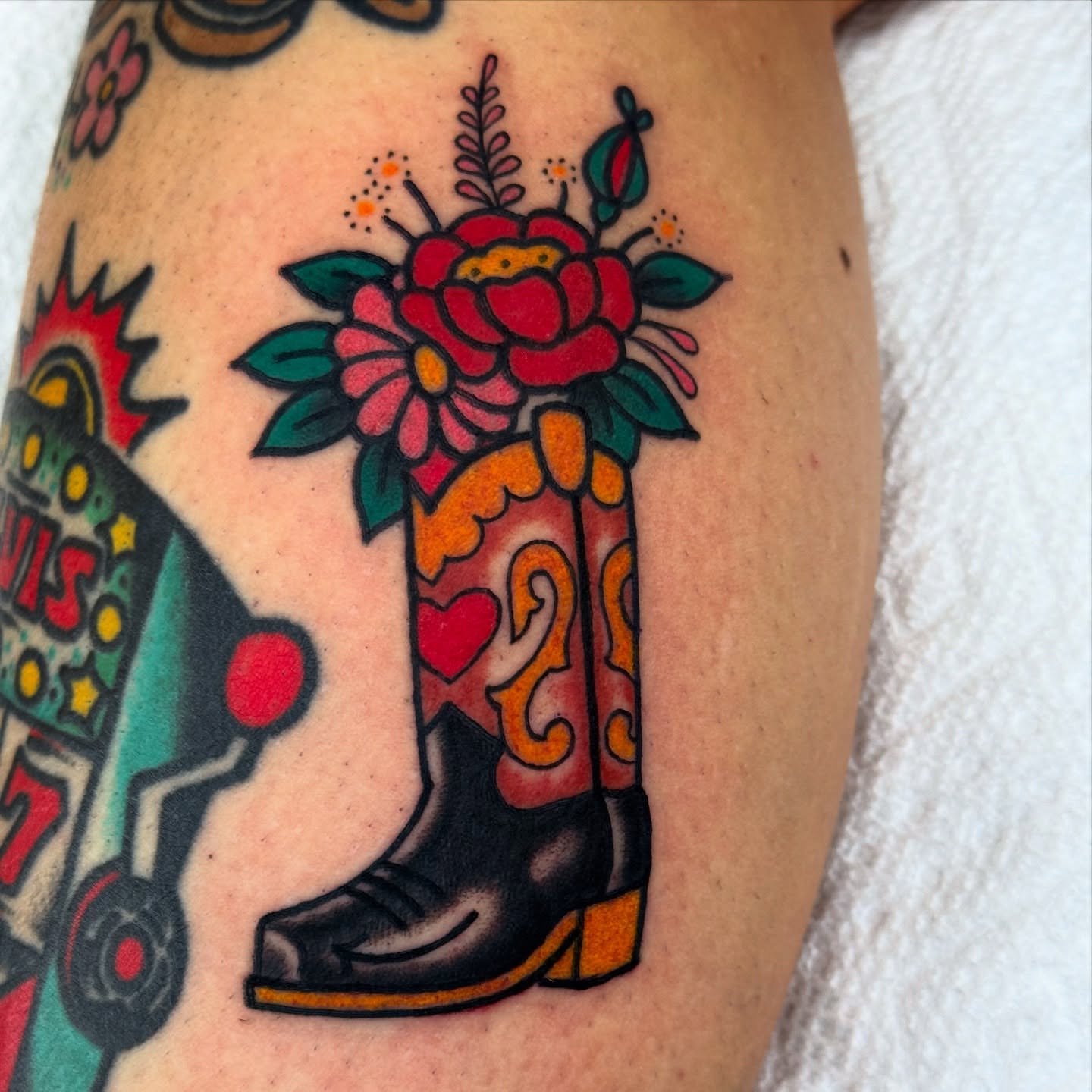 Cowboy boot with floral bouquet American traditional tattoo on the forearm by Lisa Del Toro