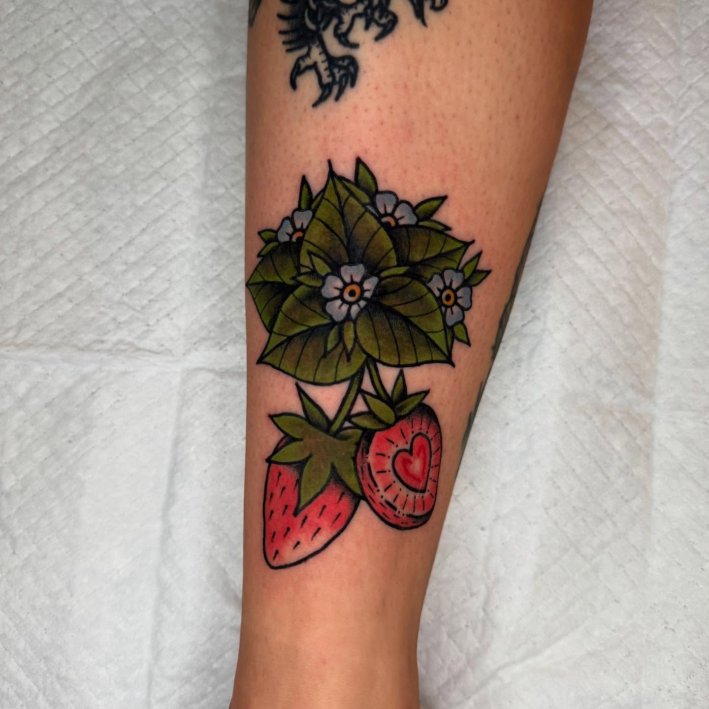 Strawberry and flowers American traditional tattoo on the forearm by Atom Aker