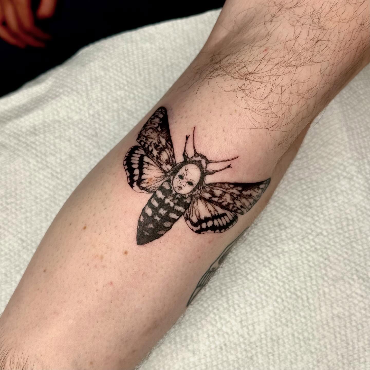 Moth with human face dark realism tattoo on the forearm by taline