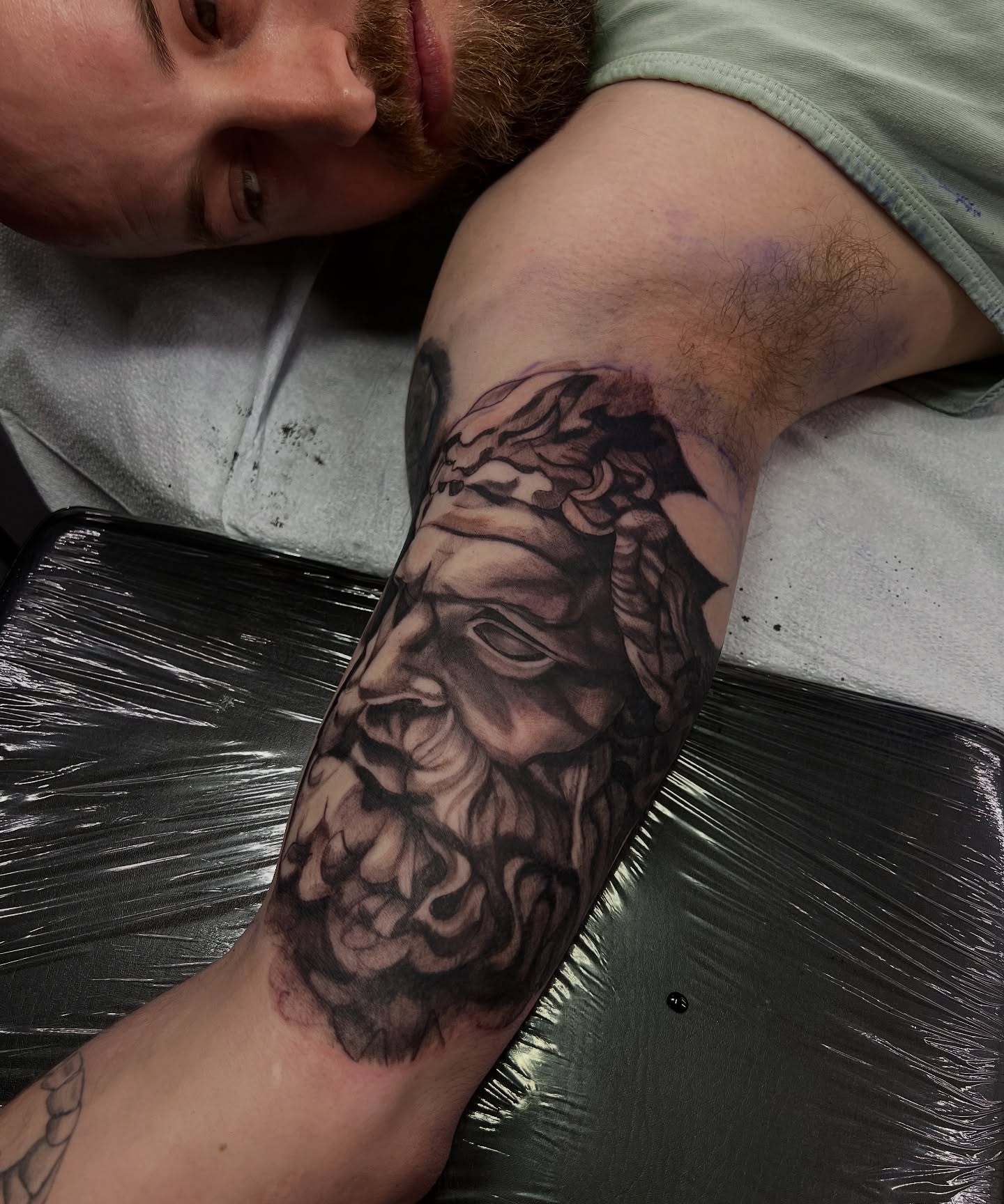 Bearded man's face black and grey tattoo on the forearm by Daphne Landry