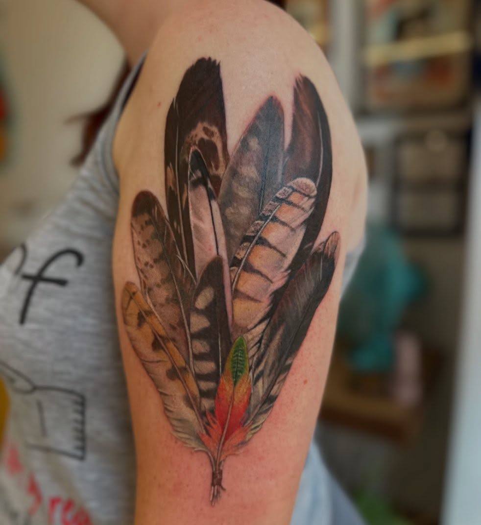 Feather arrangement realism tattoo on the upper arm by Abigail Townsend
