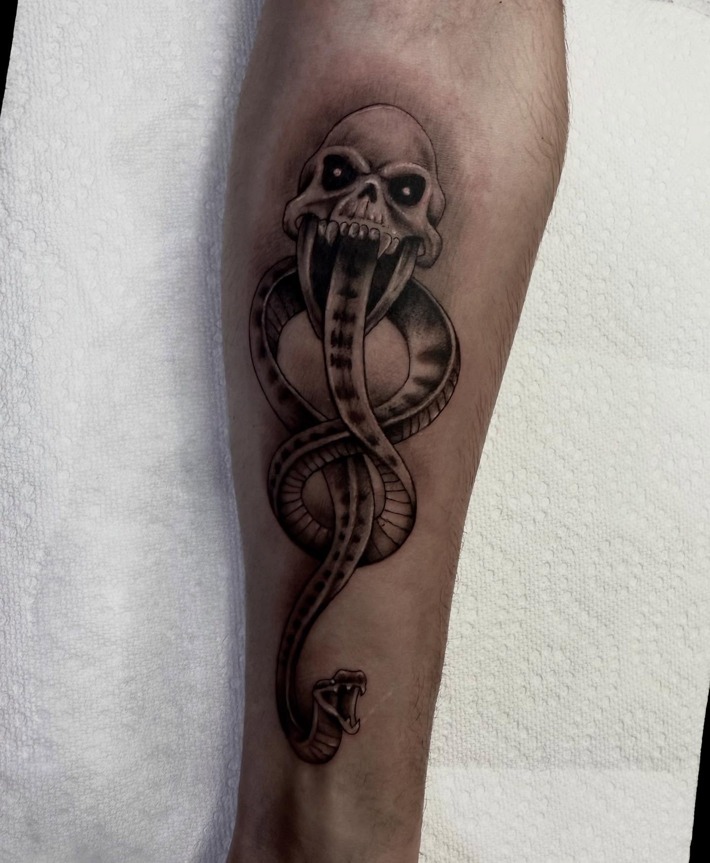 Snake and skull black and grey tattoo on the forearm by Jameson William Cowan