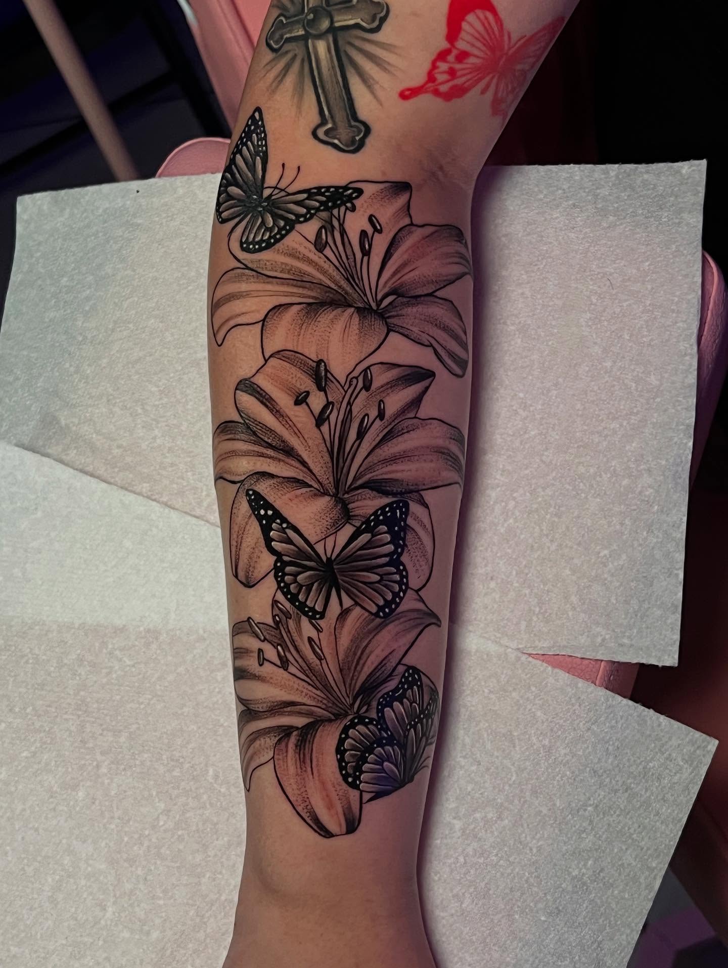 Lilies and butterflies realism tattoo on the forearm by Jasmin Lozano