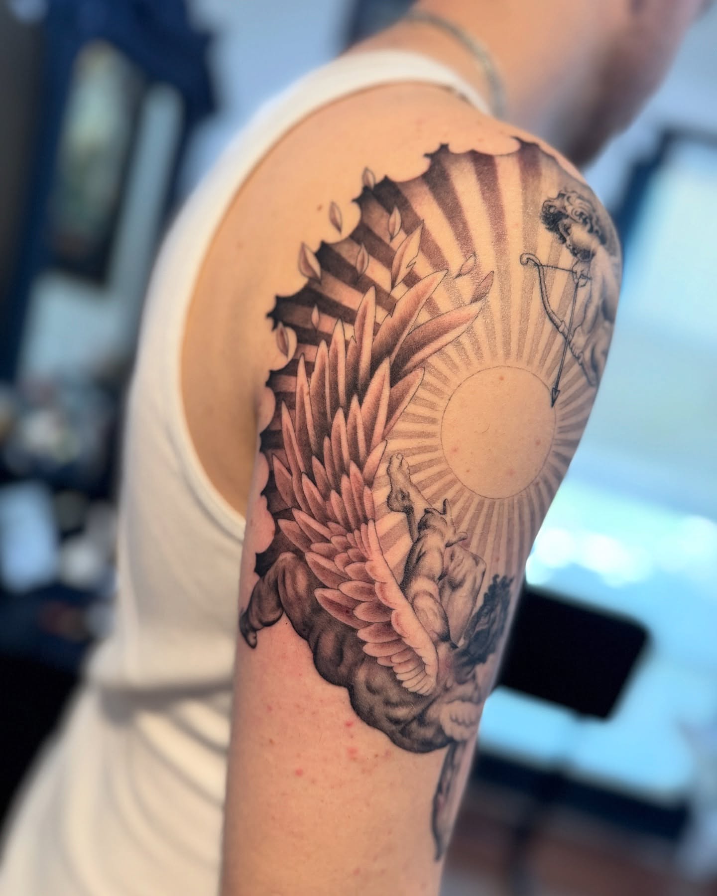 Sunburst and angel realism tattoo on the shoulder by Julio Ferrer