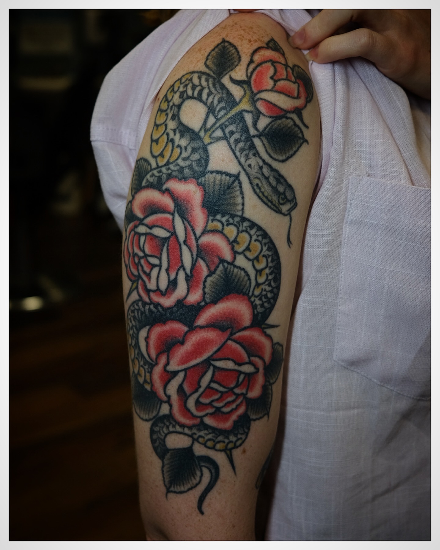 Snake and roses American traditional tattoo on the upper arm by Tony Talbert, Fredericksburg, Virginia