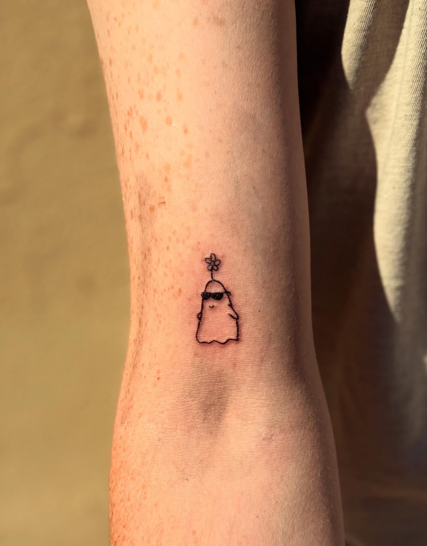 Ghost with flower crown fine line tattoo on the forearm by Kylee Snow
