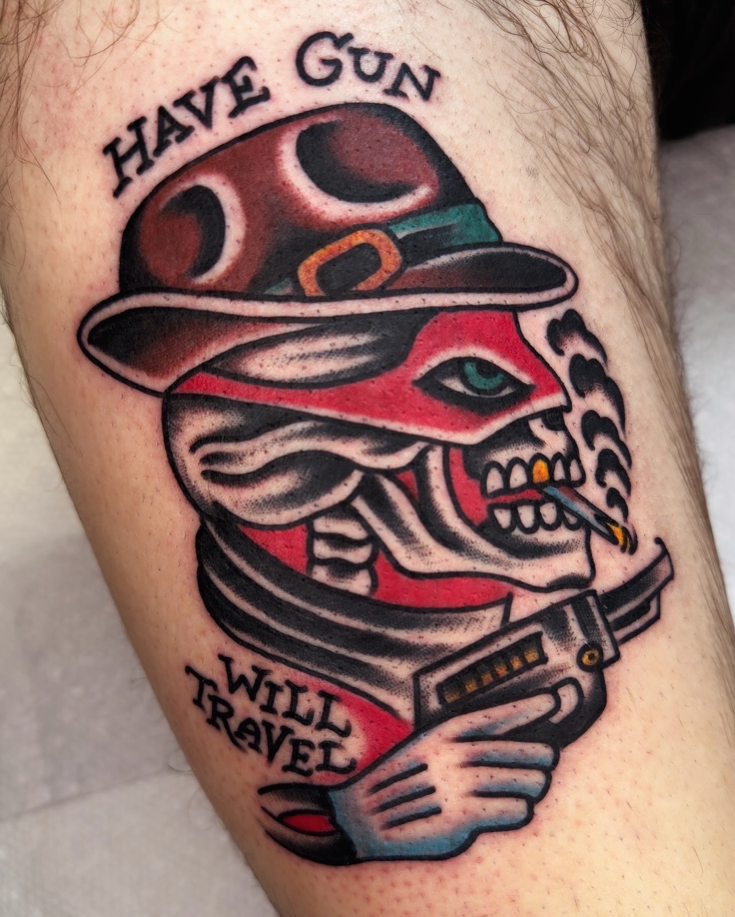 Skull with hat and gun American traditional tattoo on the thigh by Tony Kaplan