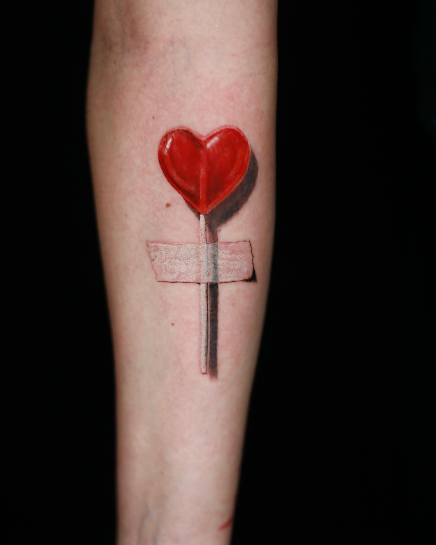 Heart lollipop realism tattoo on the forearm by memo