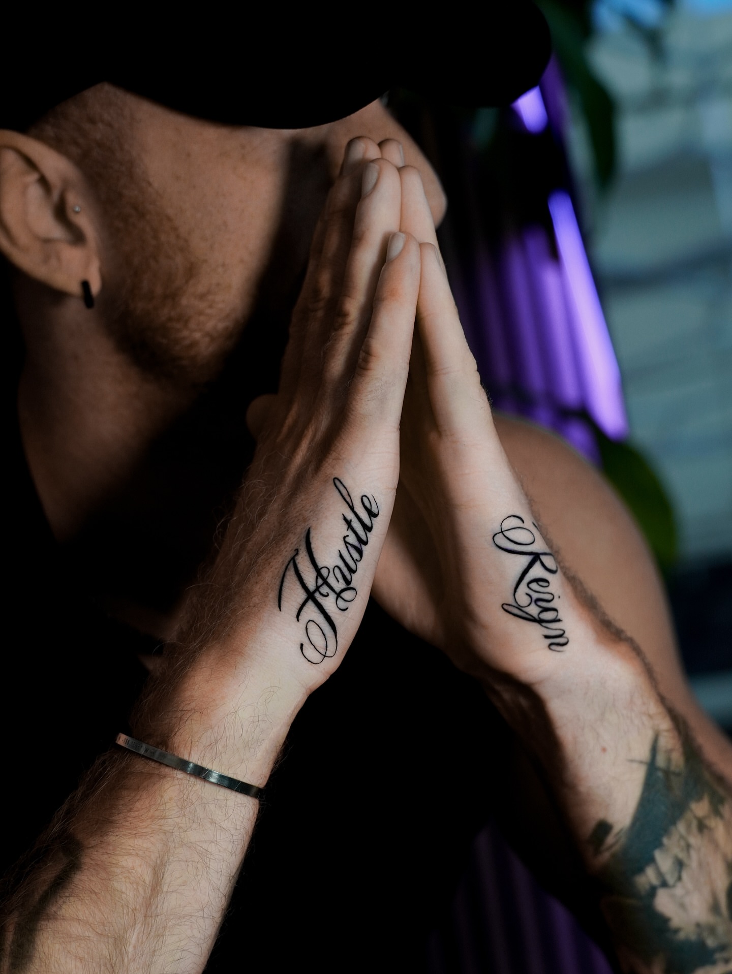 Hustle and Reign lettering script tattoo on the hand by Sophia Delfino