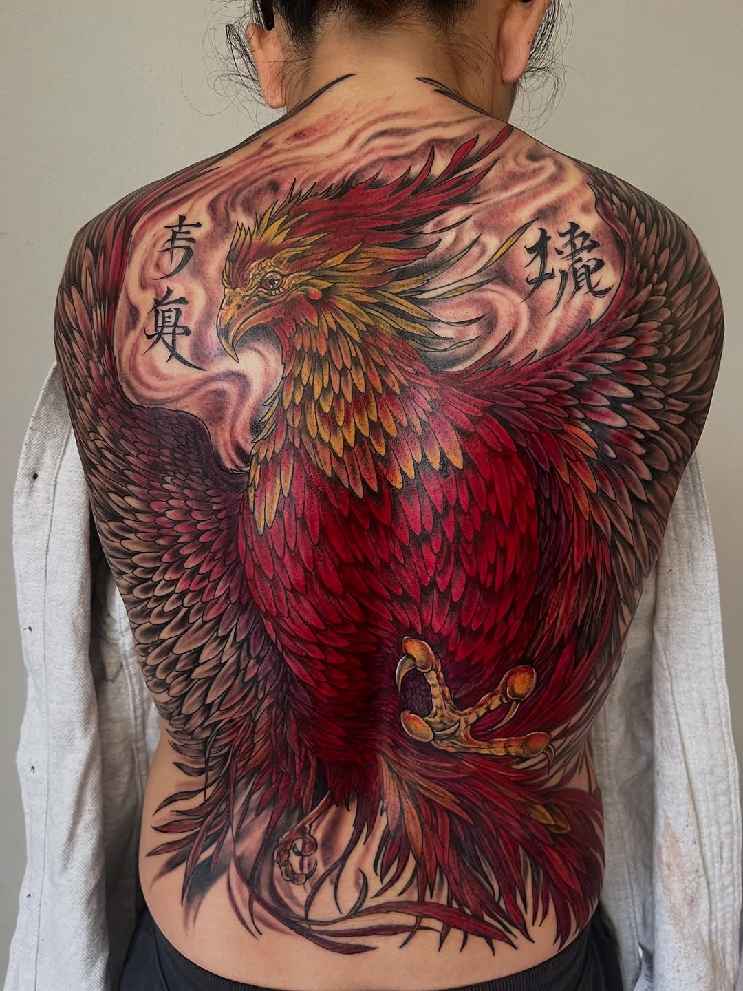 Phoenix with chinese characters realism tattoo on the back by Janelle Cuba