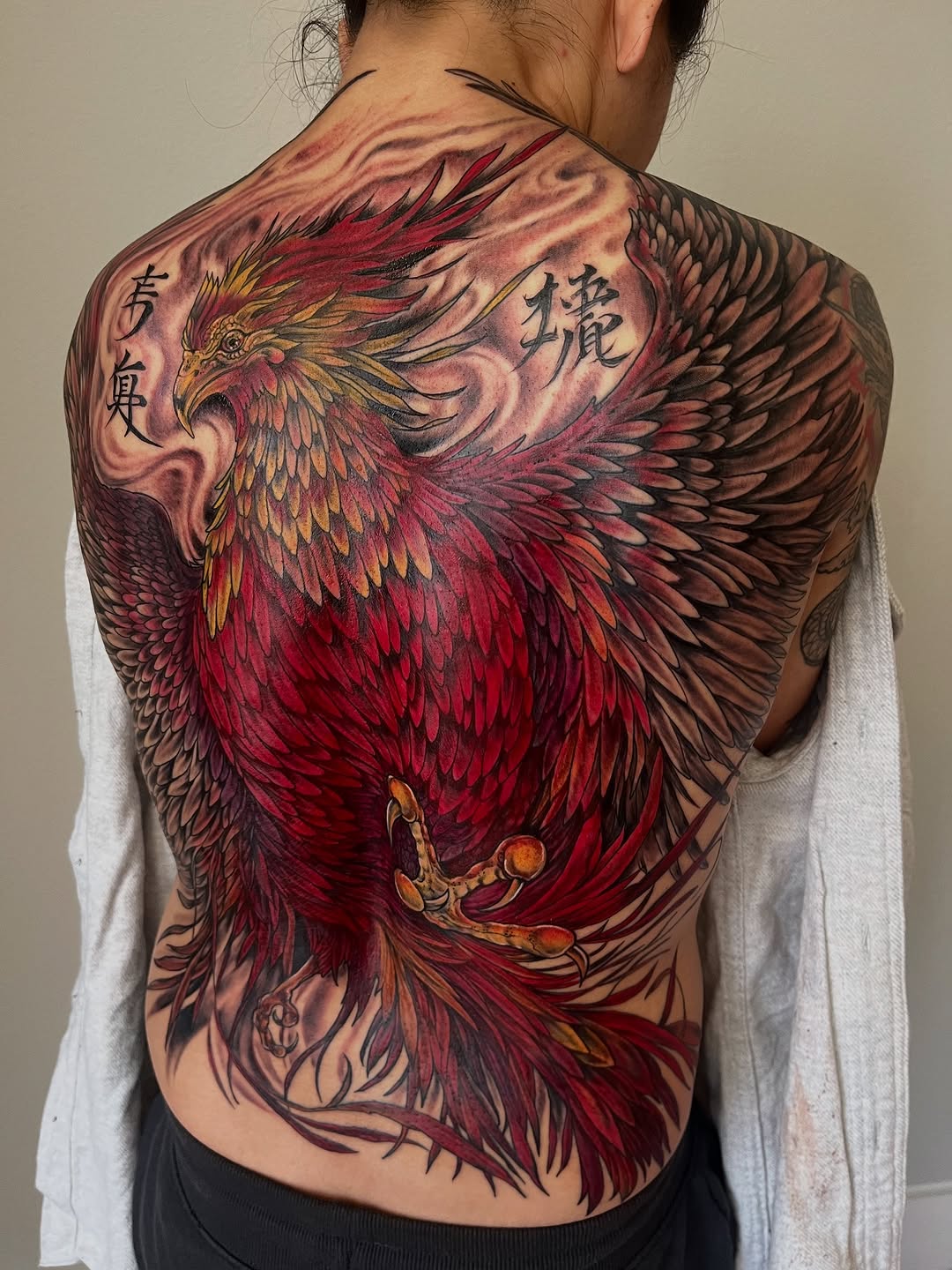 Phoenix with script realism tattoo on the back by Janelle Cuba