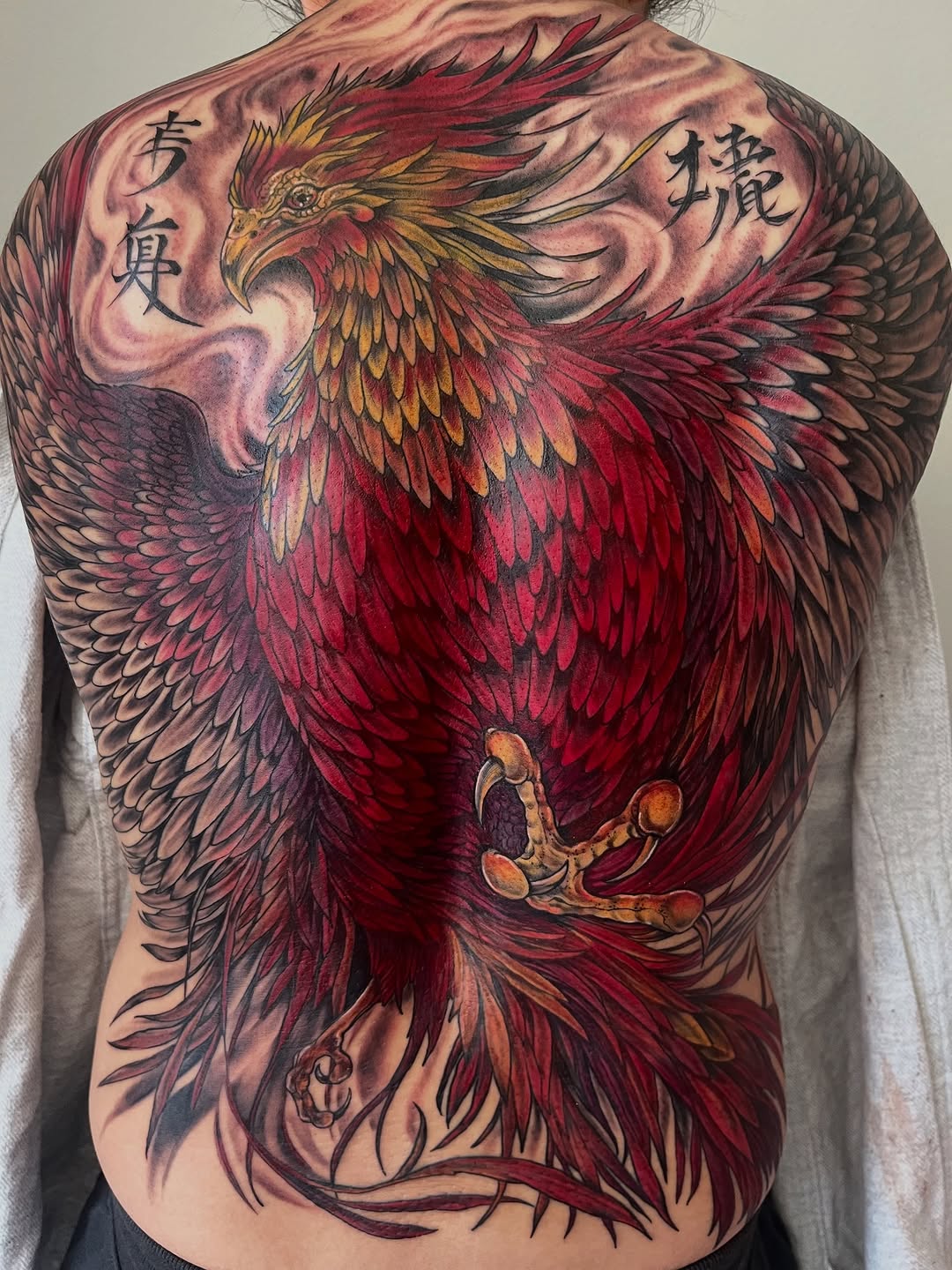 Phoenix with script realism tattoo on the back by Janelle Cuba