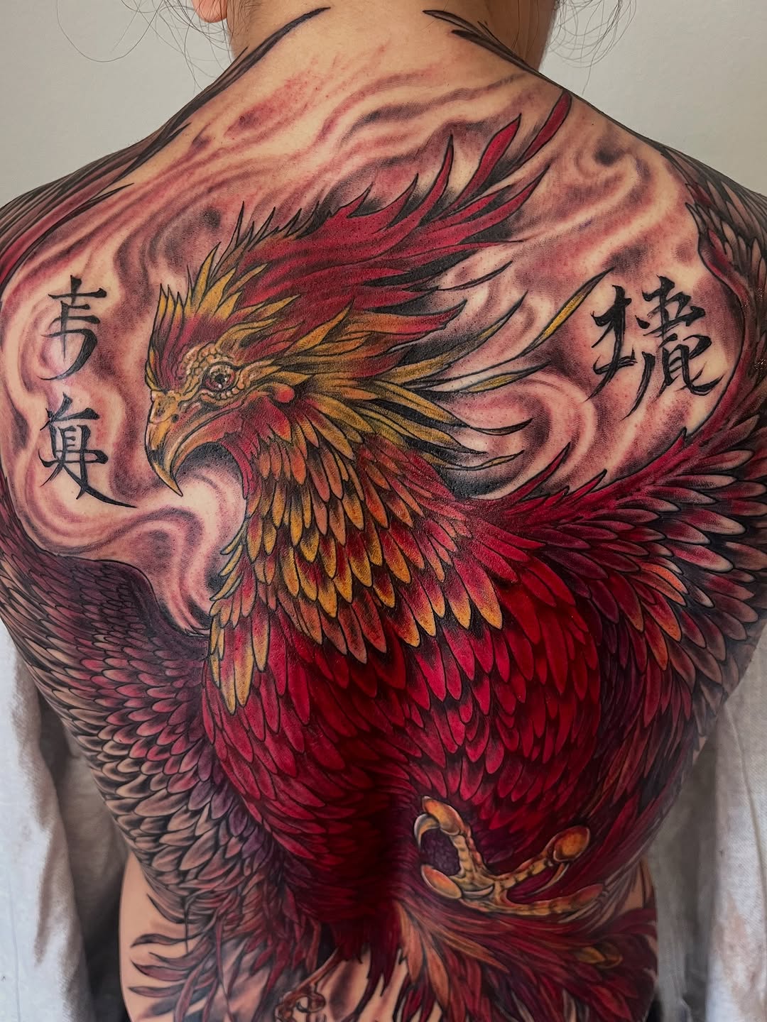 Phoenix with script realism tattoo on the back by Janelle Cuba